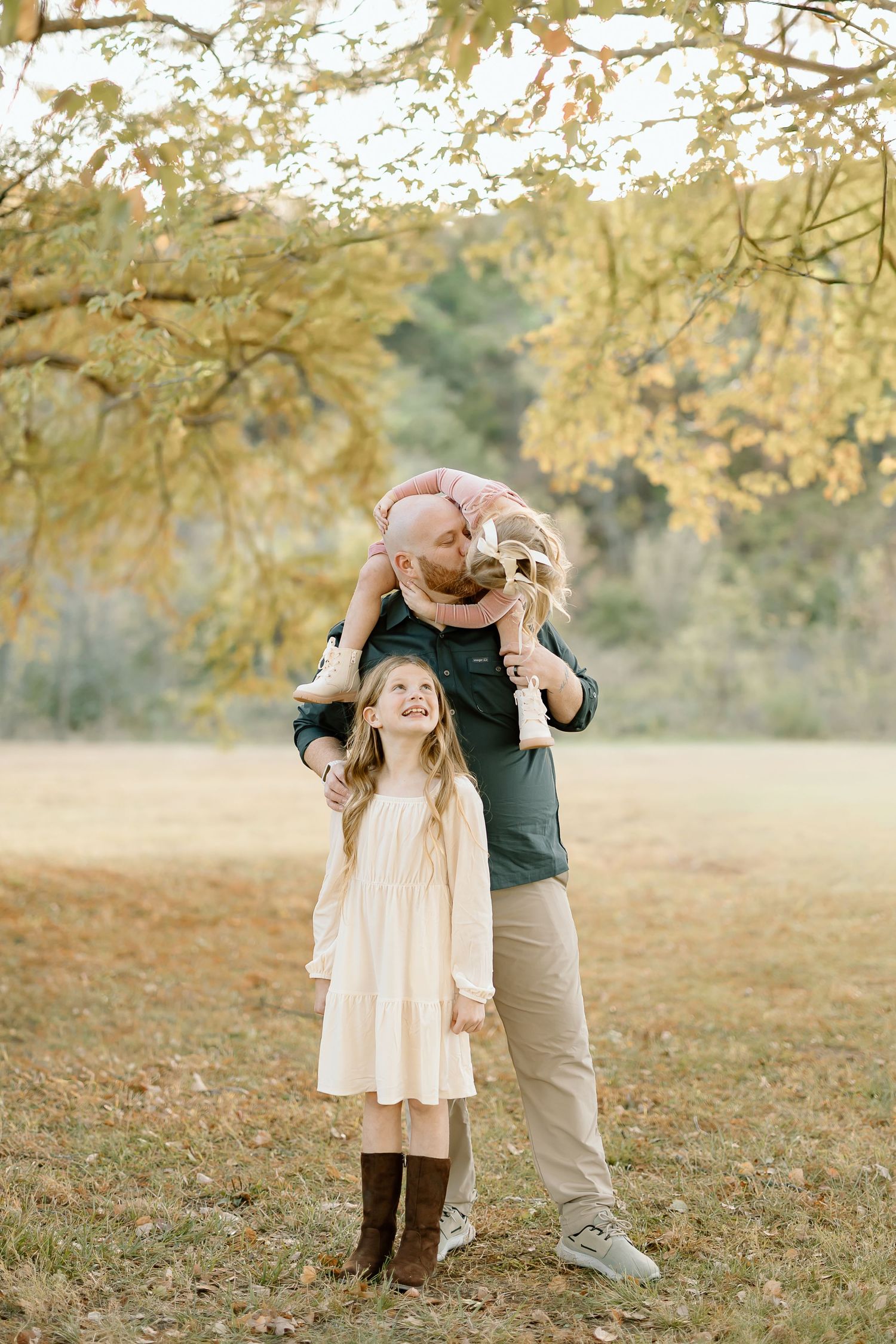 Sweet autumn outdoor photo series showing tender moments between parent and child under golden tree branches.