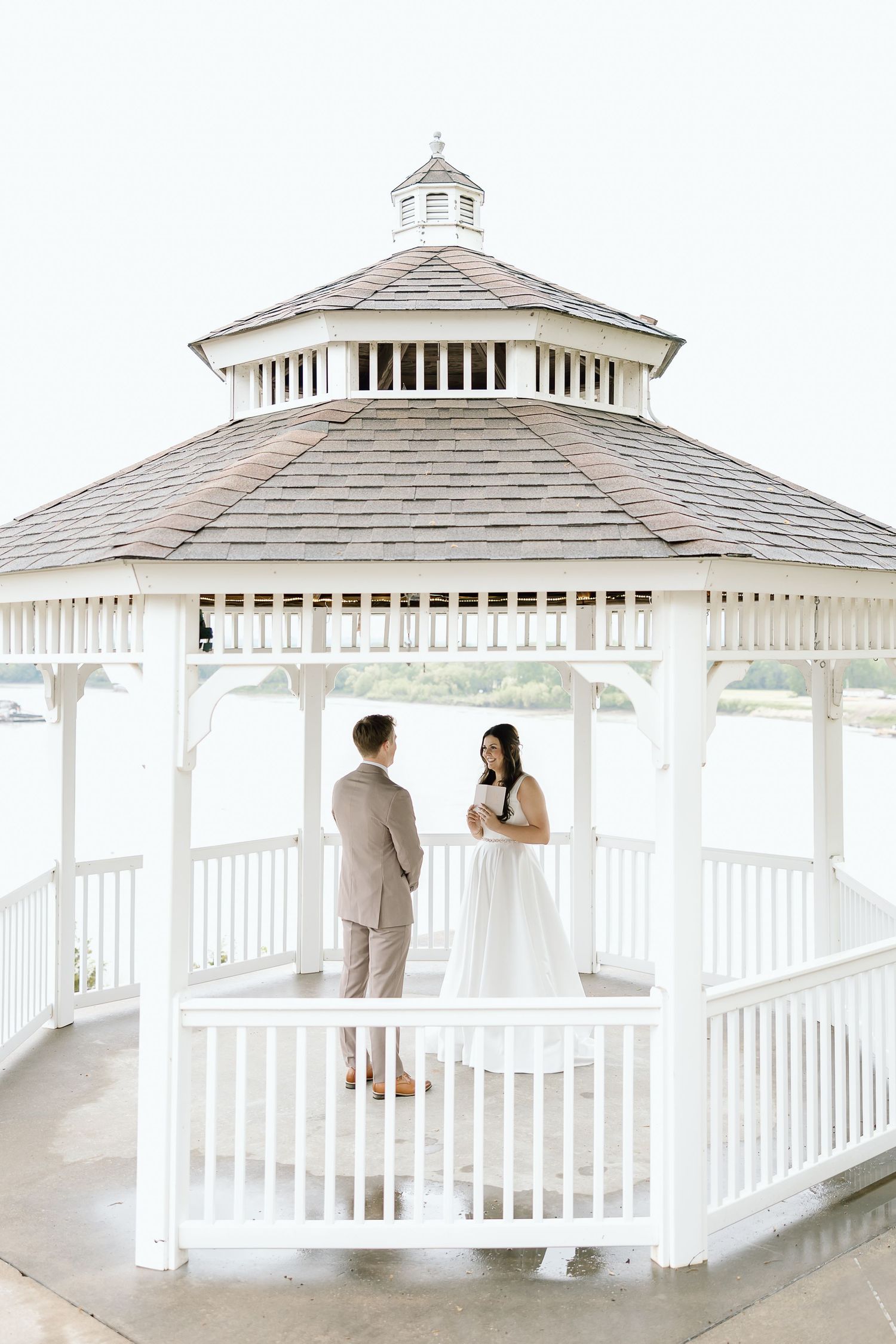 Romantic wedding couple shares intimate moments in white gazebos overlooking the ocean on their special day.