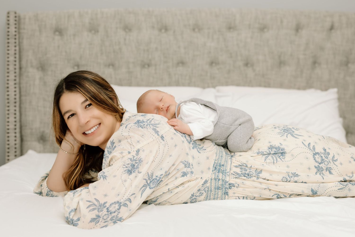 A person sleeping peacefully under white and blue floral bedding in a cozy bedroom setting.