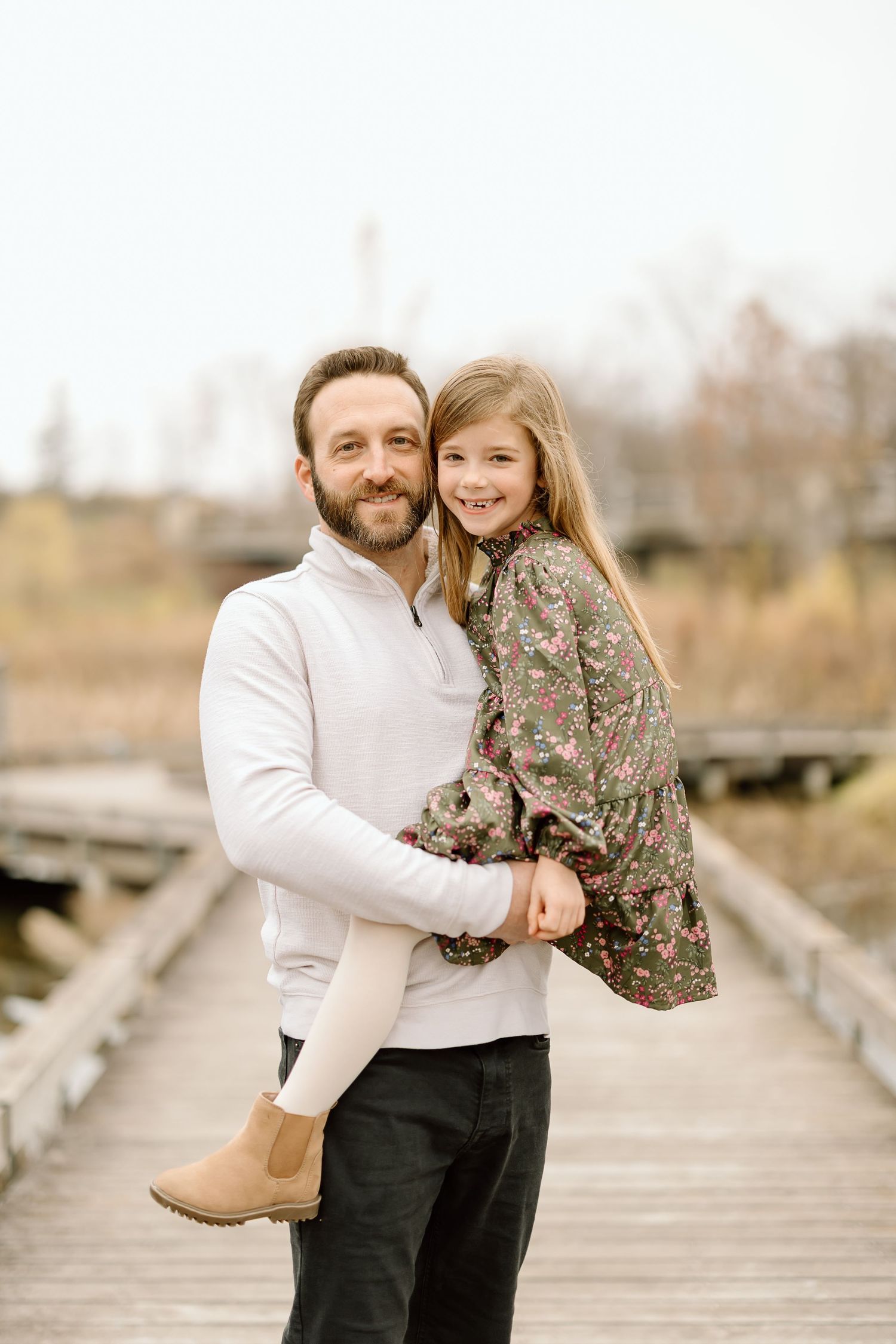 A parent and child share a joyful moment together on a wooden boardwalk.