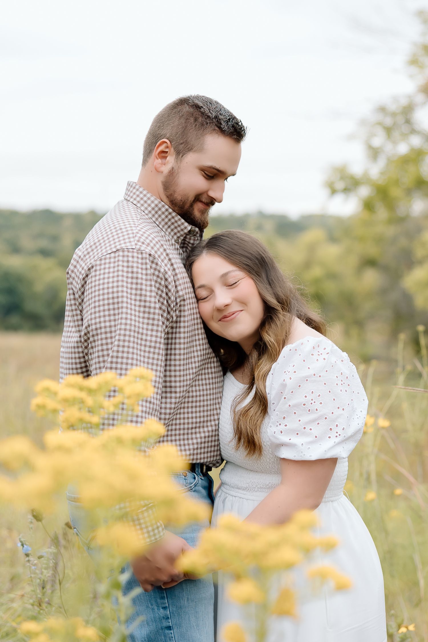 Sweet candid moment captured between couple in casual attire surrounded by yellow blooms.