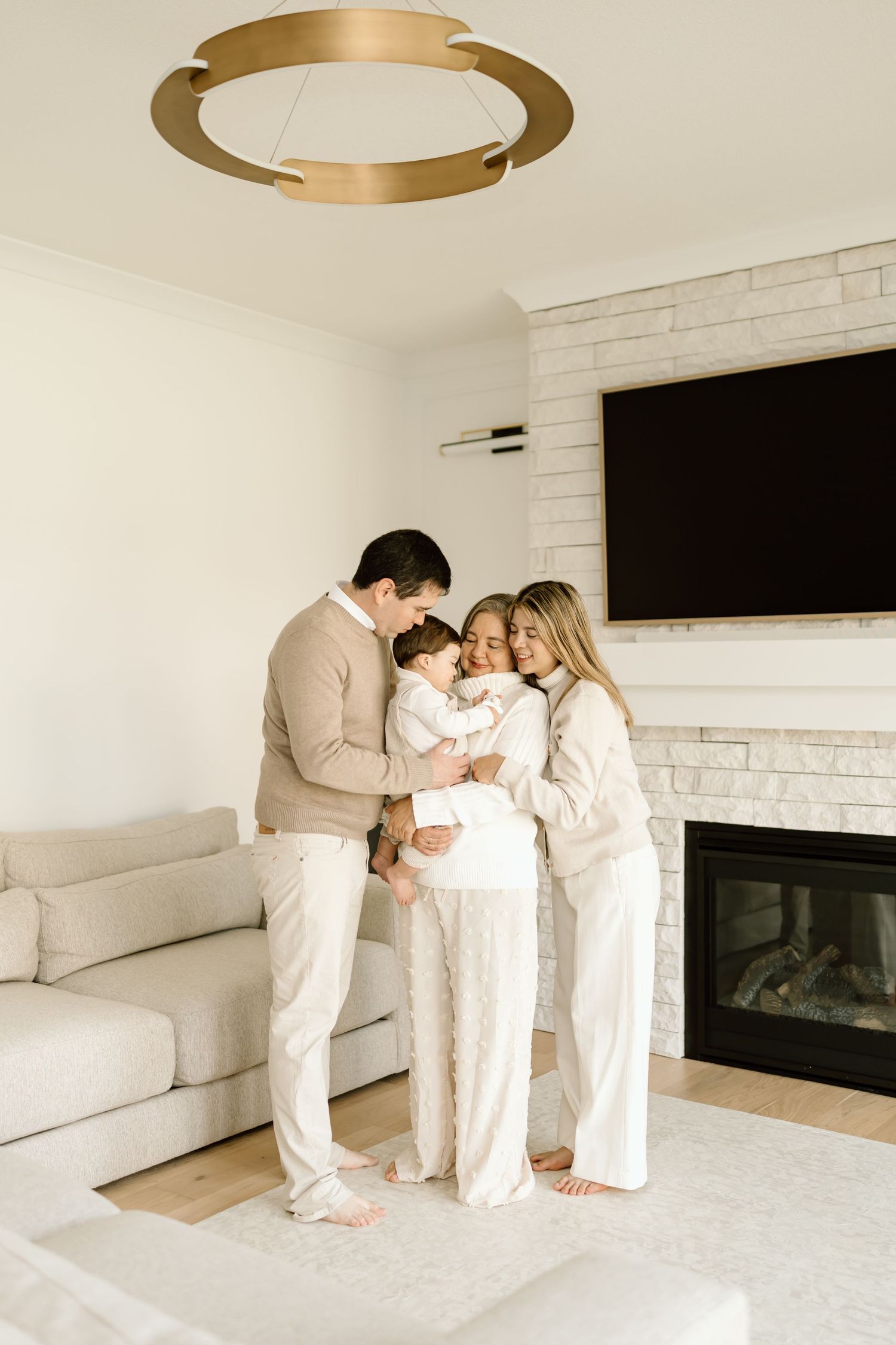 A cozy family moment in a modern white living room with fireplace and circular gold ceiling light fixture.