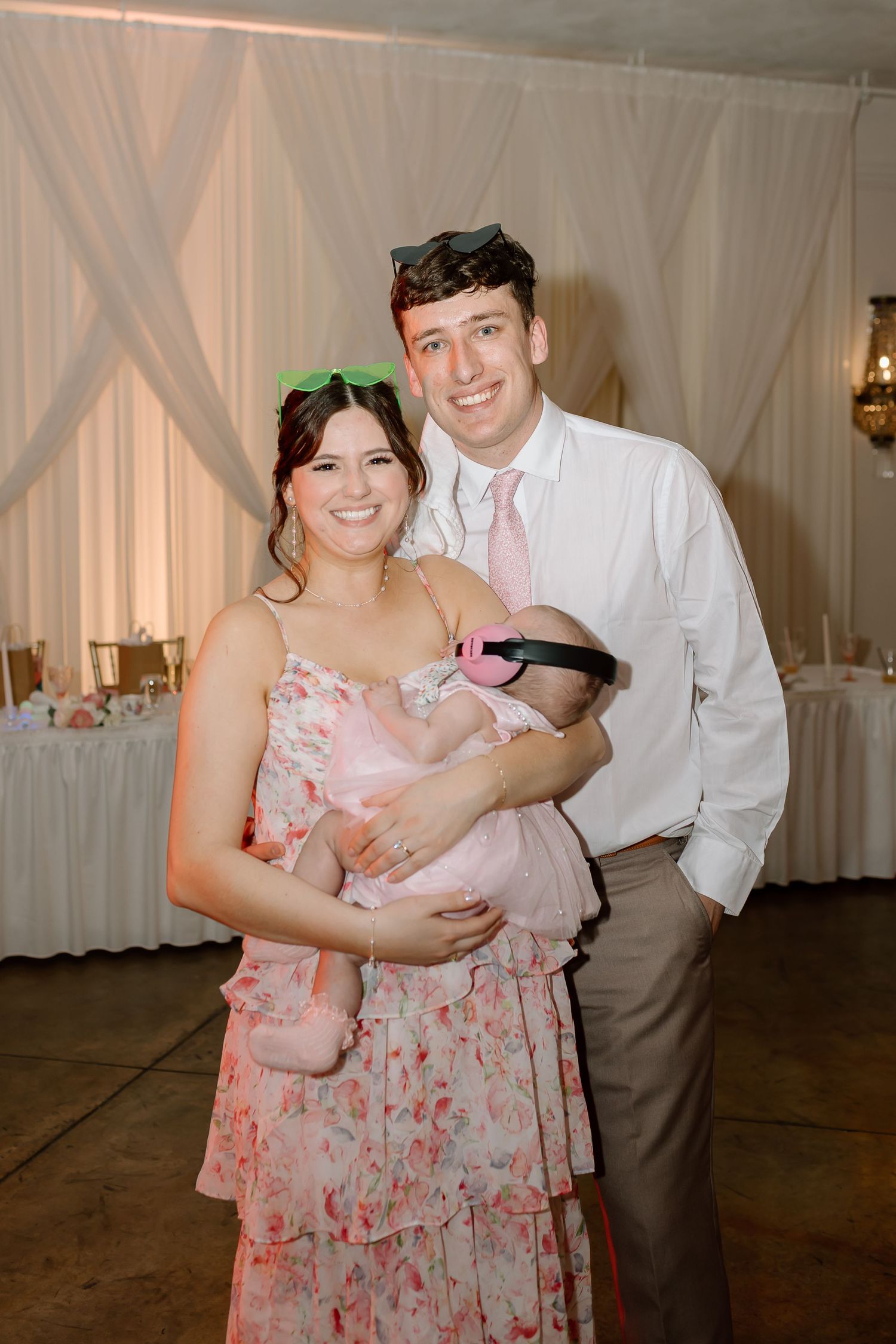 A couple dances together at a wedding reception venue with white draped fabric walls in the background.