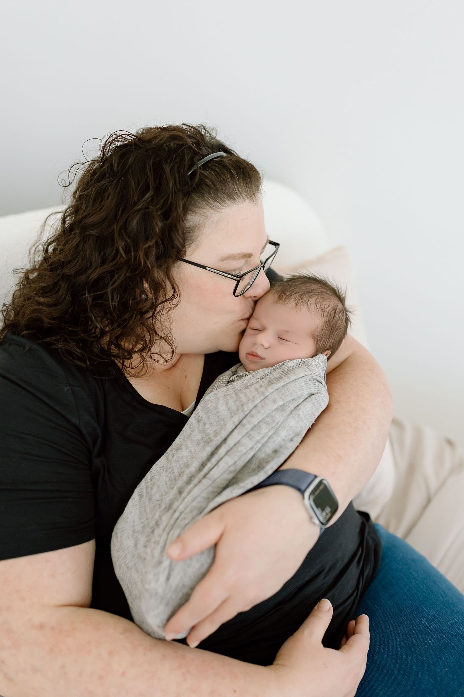 Intimate black and white portrait showing gentle embrace against neutral background.