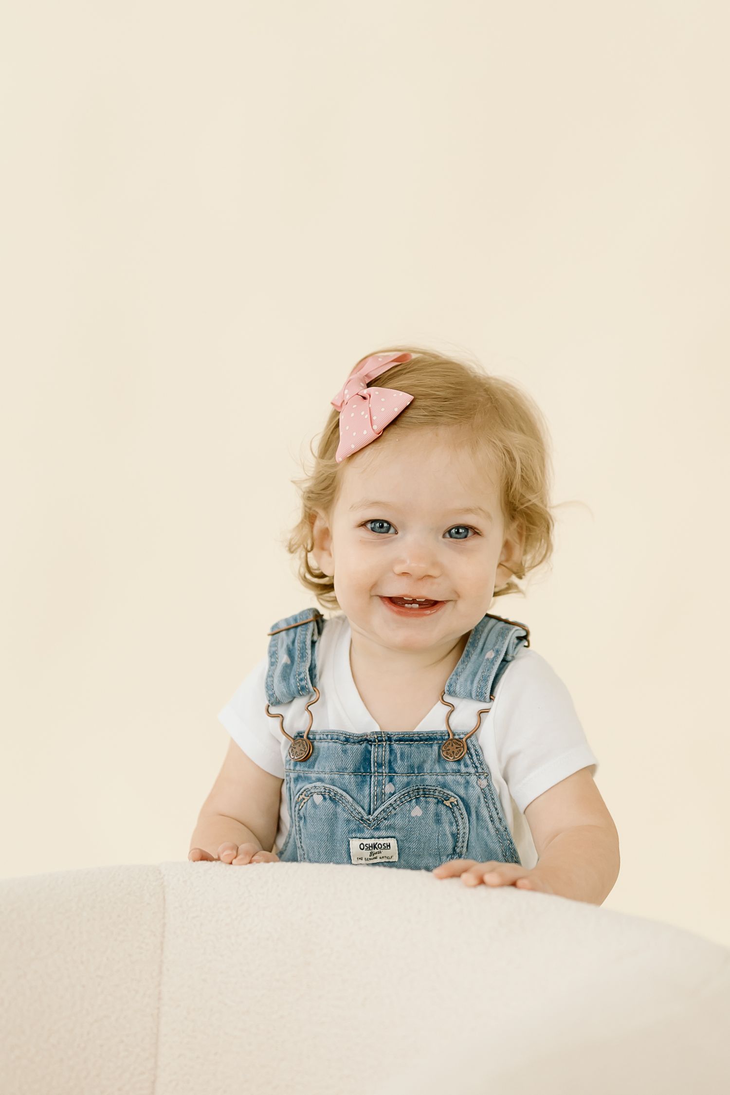 Sweet toddler in denim overalls and white shirt smiles joyfully in a series of candid portrait photos.