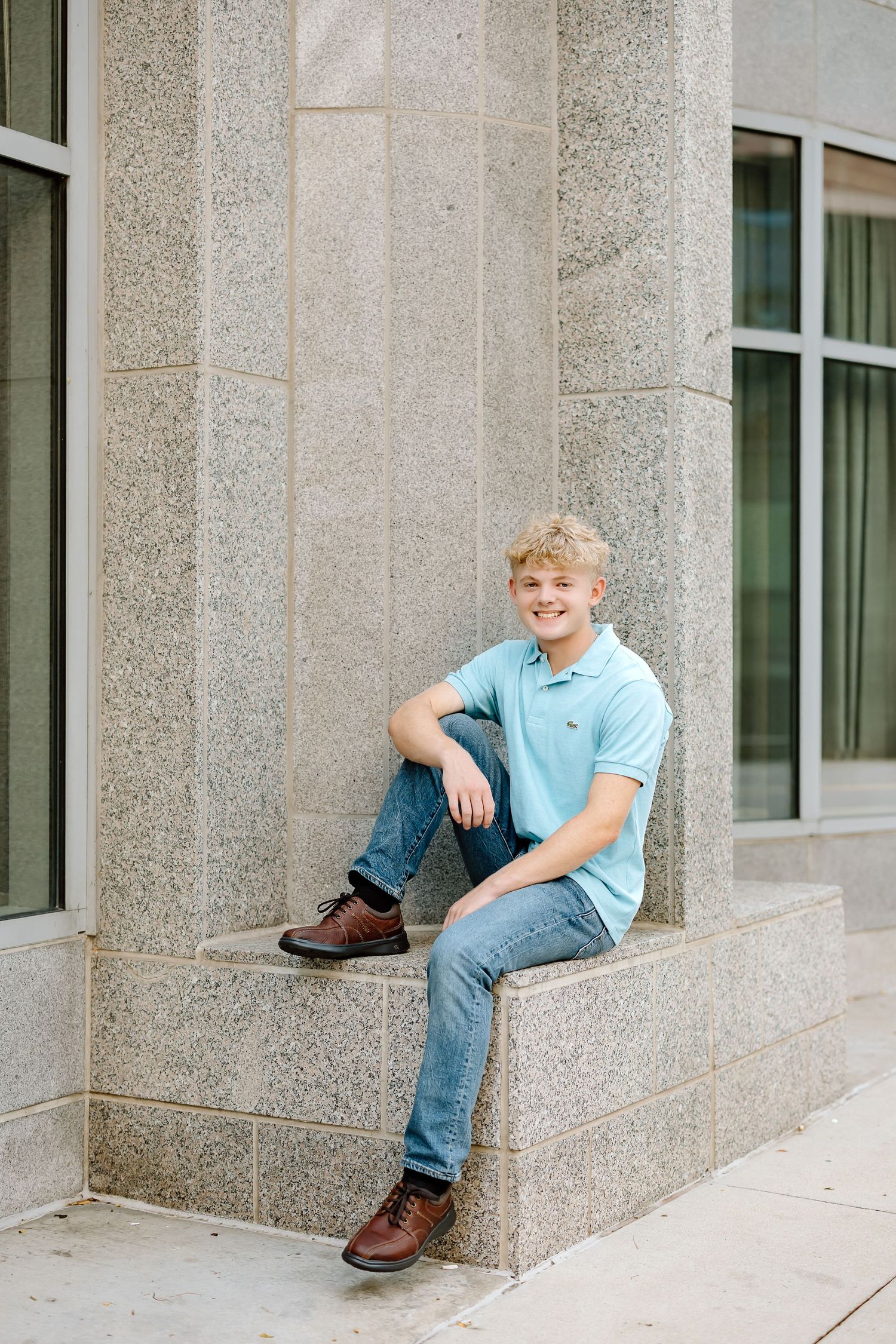 A series of four connected photos showing a child in blue clothing sitting and posing on stone building steps.