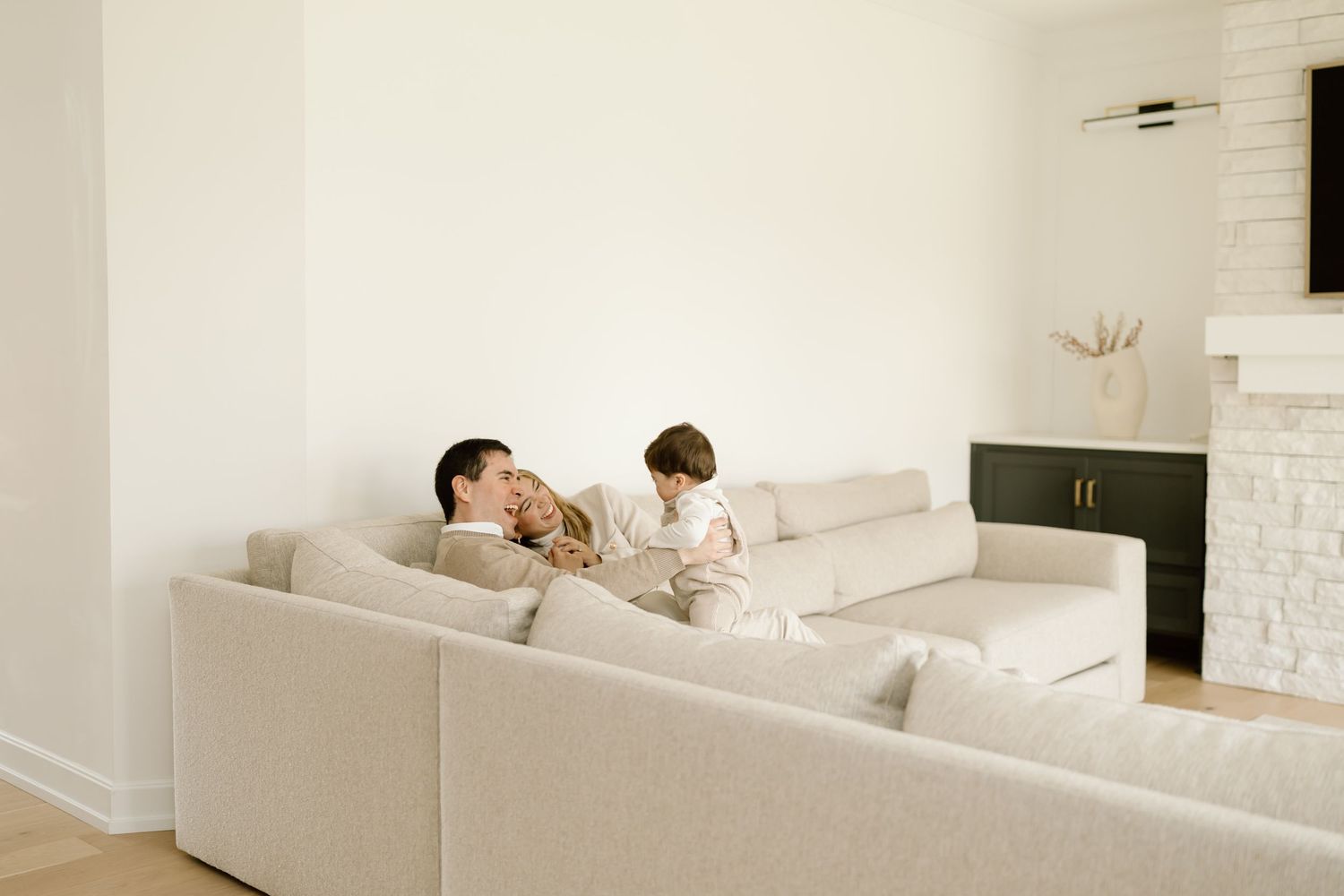 Two people relax together on a comfortable white sectional sofa in a minimalist living room with bright walls.