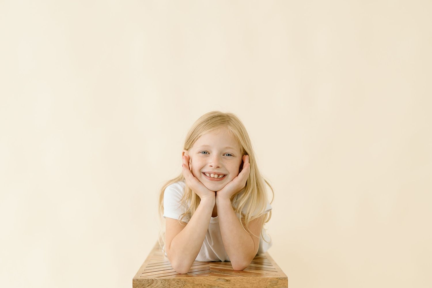 A child lies on a beige surface in four sequential poses showing playful expressions.