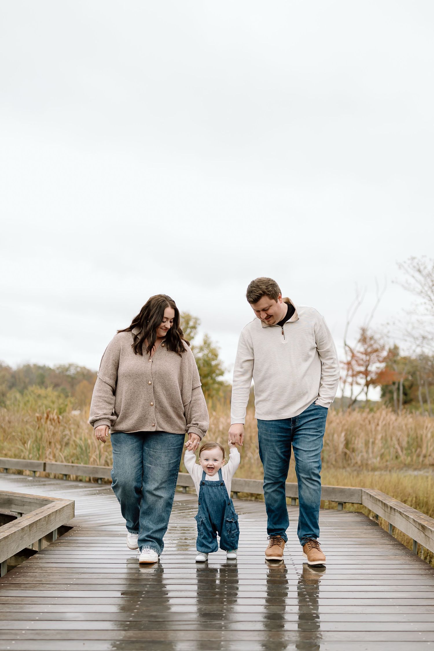 A family walks together along a wooden boardwalk on a cloudy autumn day, shown in a series of connected photos.
