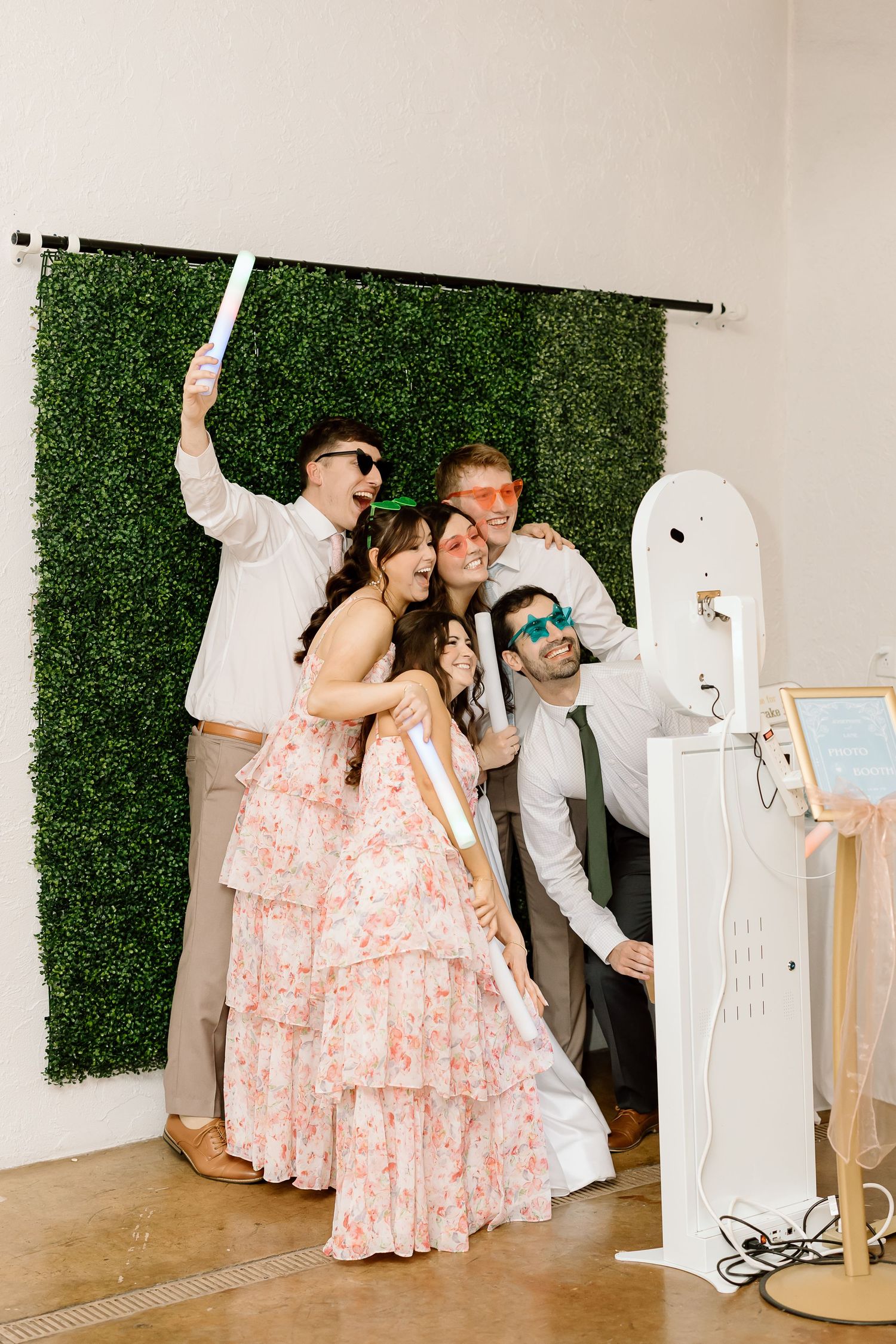 A couple in formal attire poses playfully with a white ghost-like figure at a photo booth during an event.
