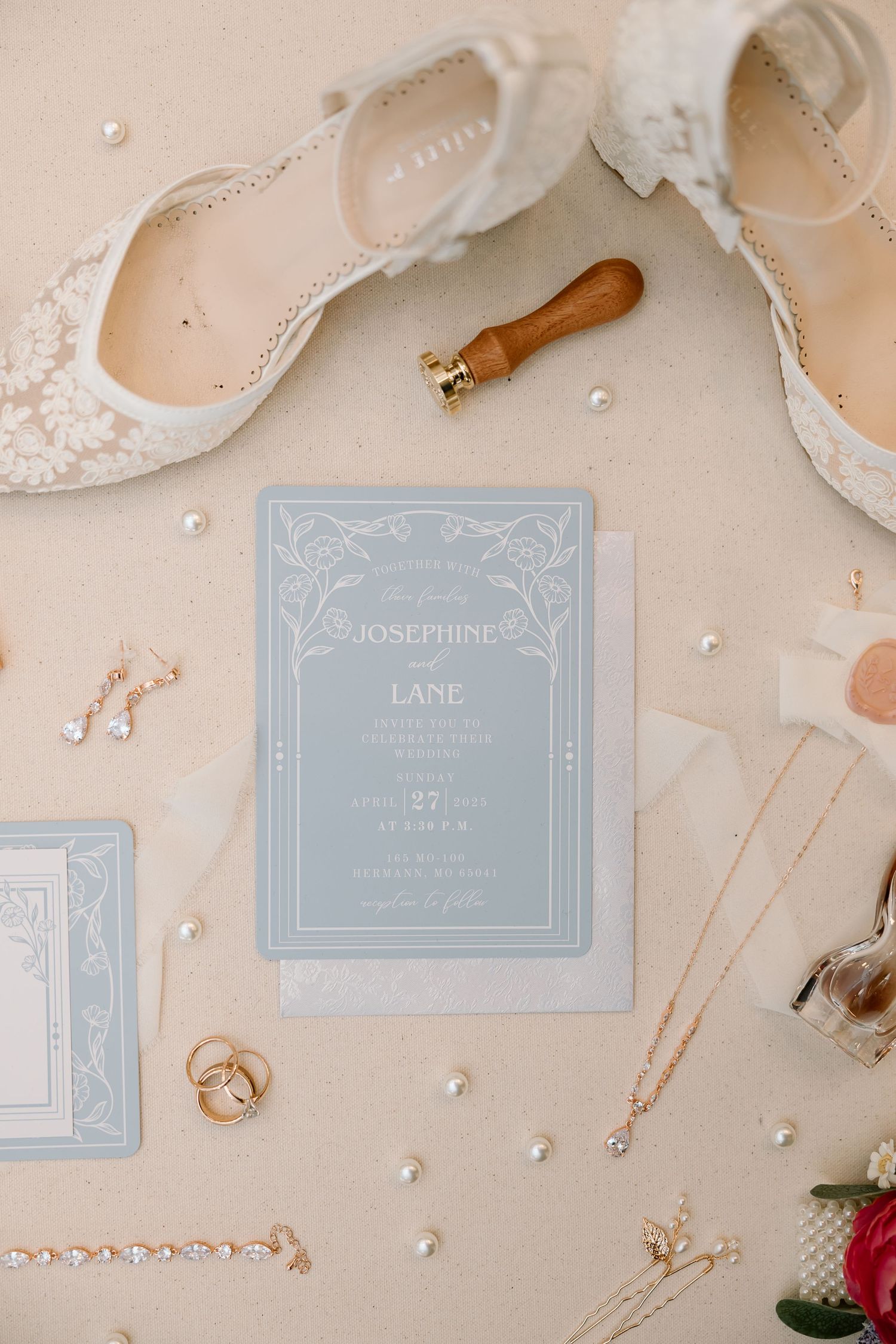Elegant wedding stationery set in pale blue and white with delicate lace details and pearl accents on beige background.