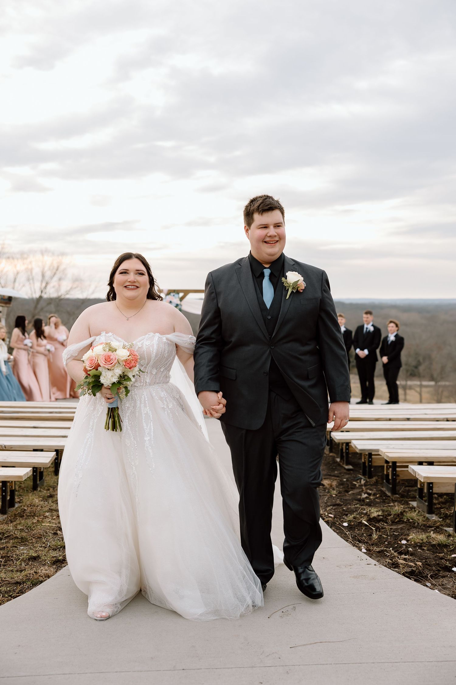 A happy couple walks together outdoors on their wedding day in matching black and white attire.