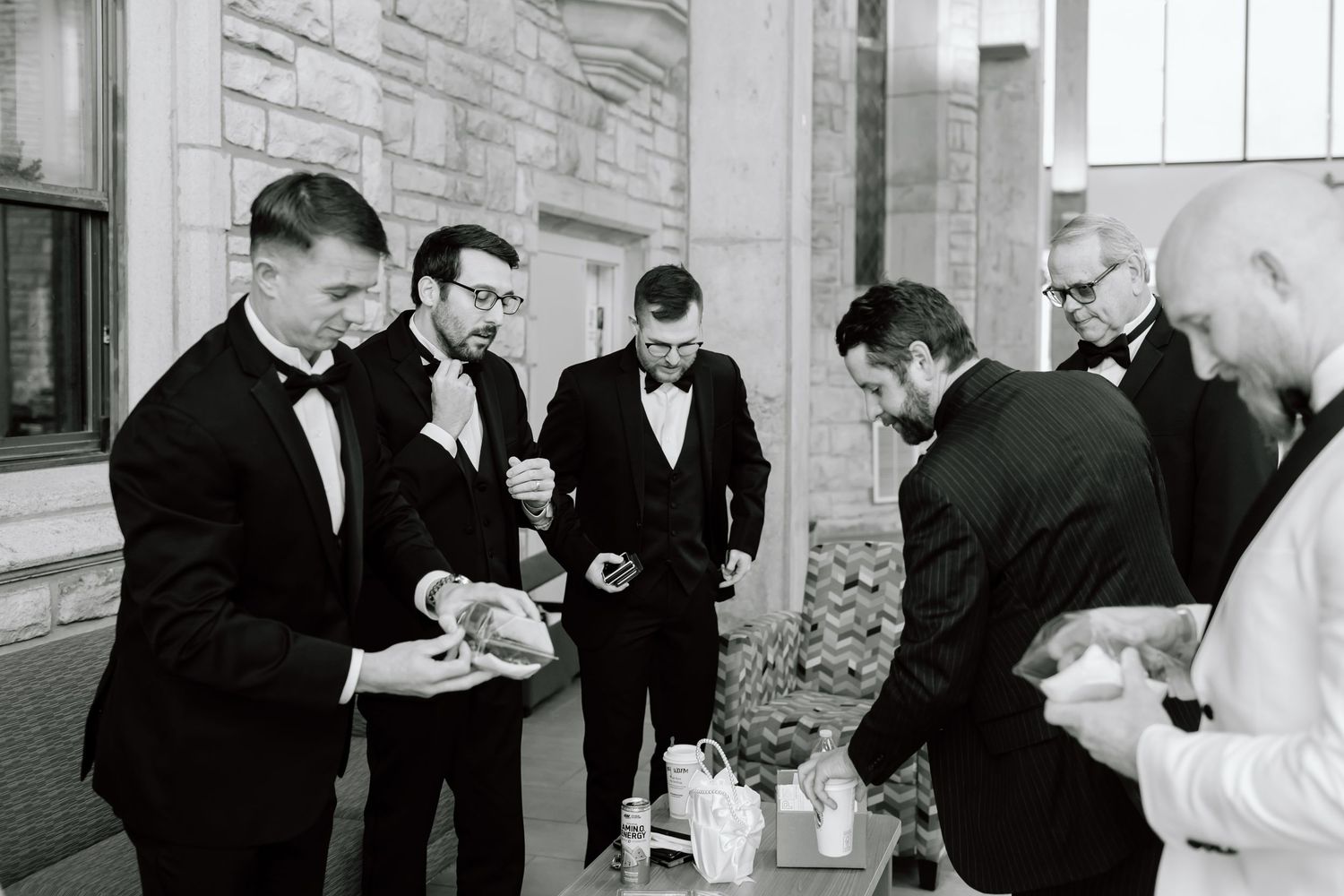People in formal black and white attire gather in conversation at an elegant indoor event.