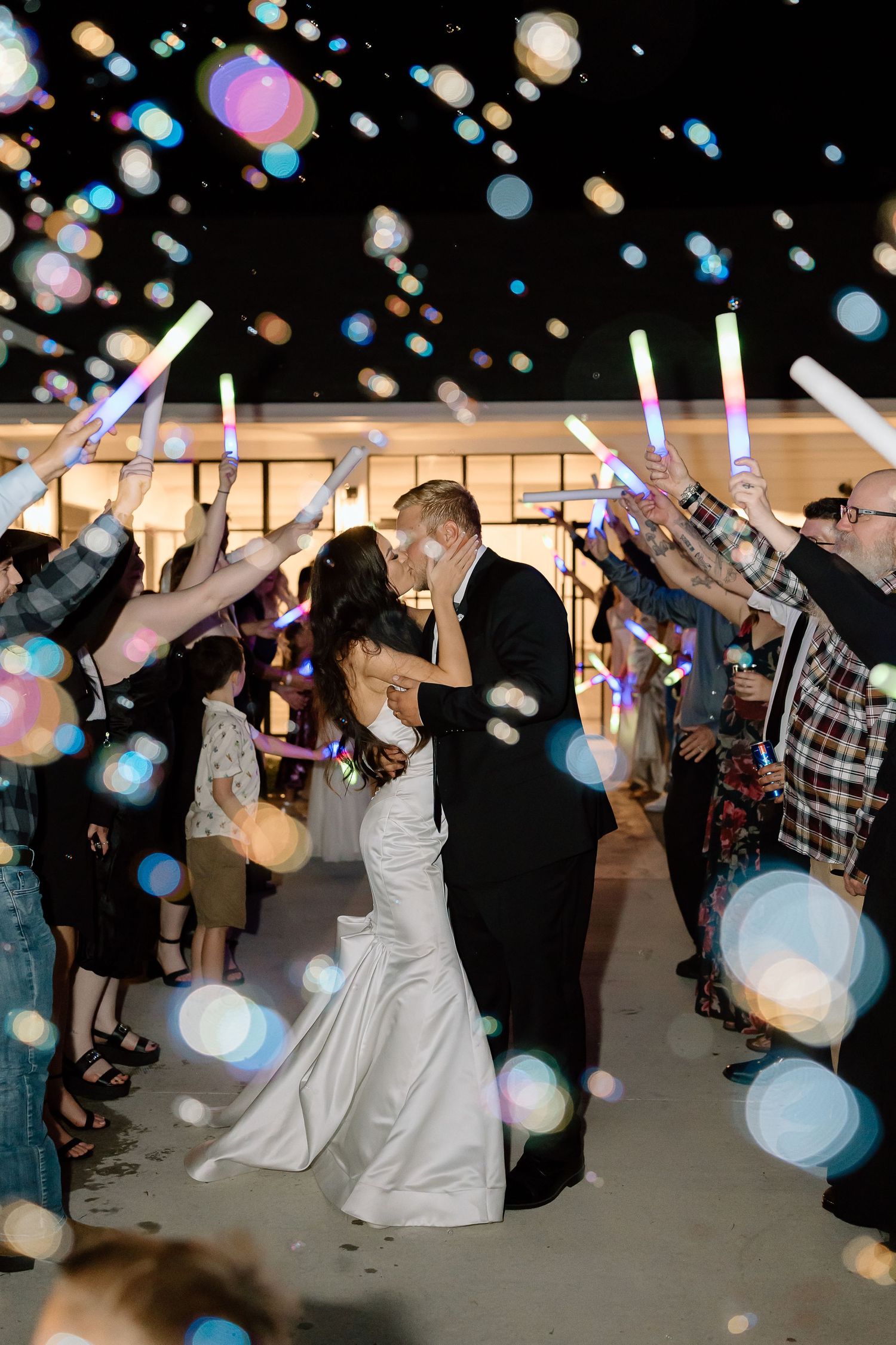 Wedding reception dance floor scene with guests celebrating under colorful bokeh lighting effects.