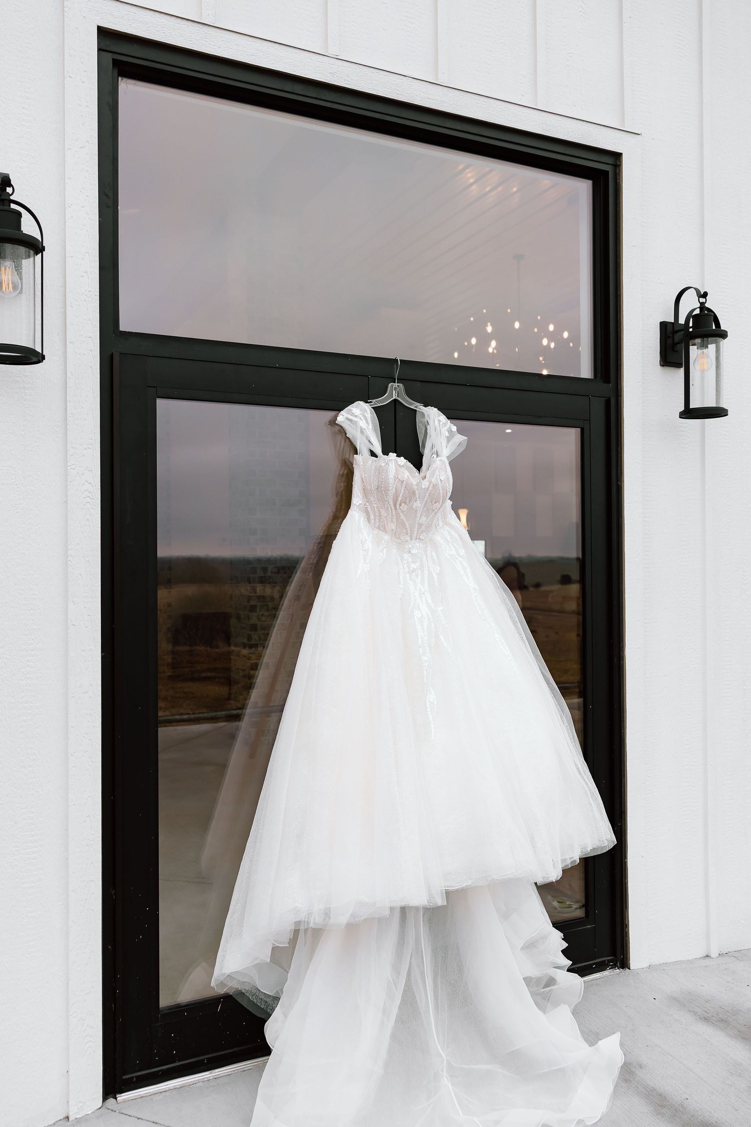 White wedding dresses displayed in a modern bridal boutique with black-framed windows and white walls.