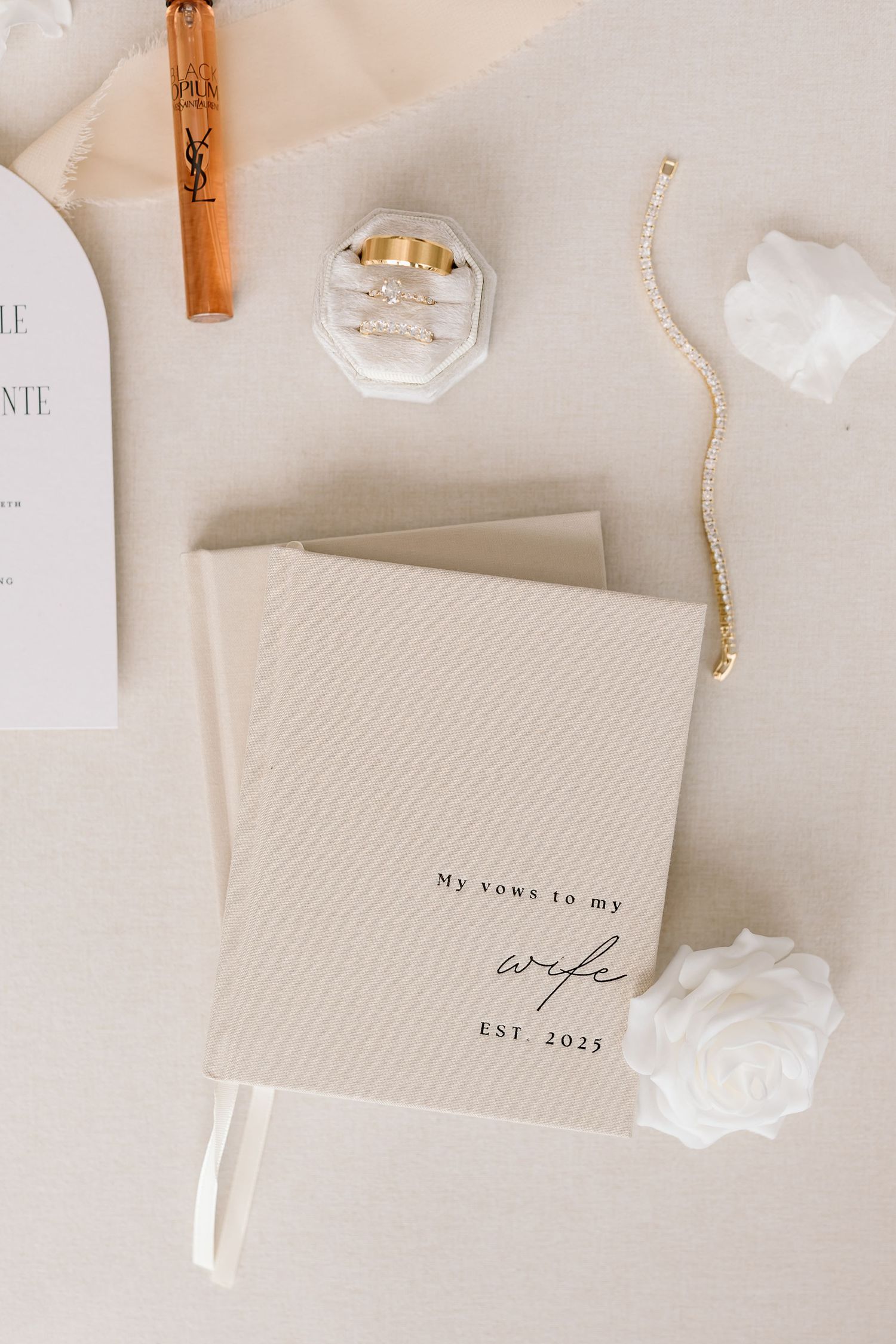 Minimalist wedding stationery in cream and white with wooden clothespins arranged on a light surface.