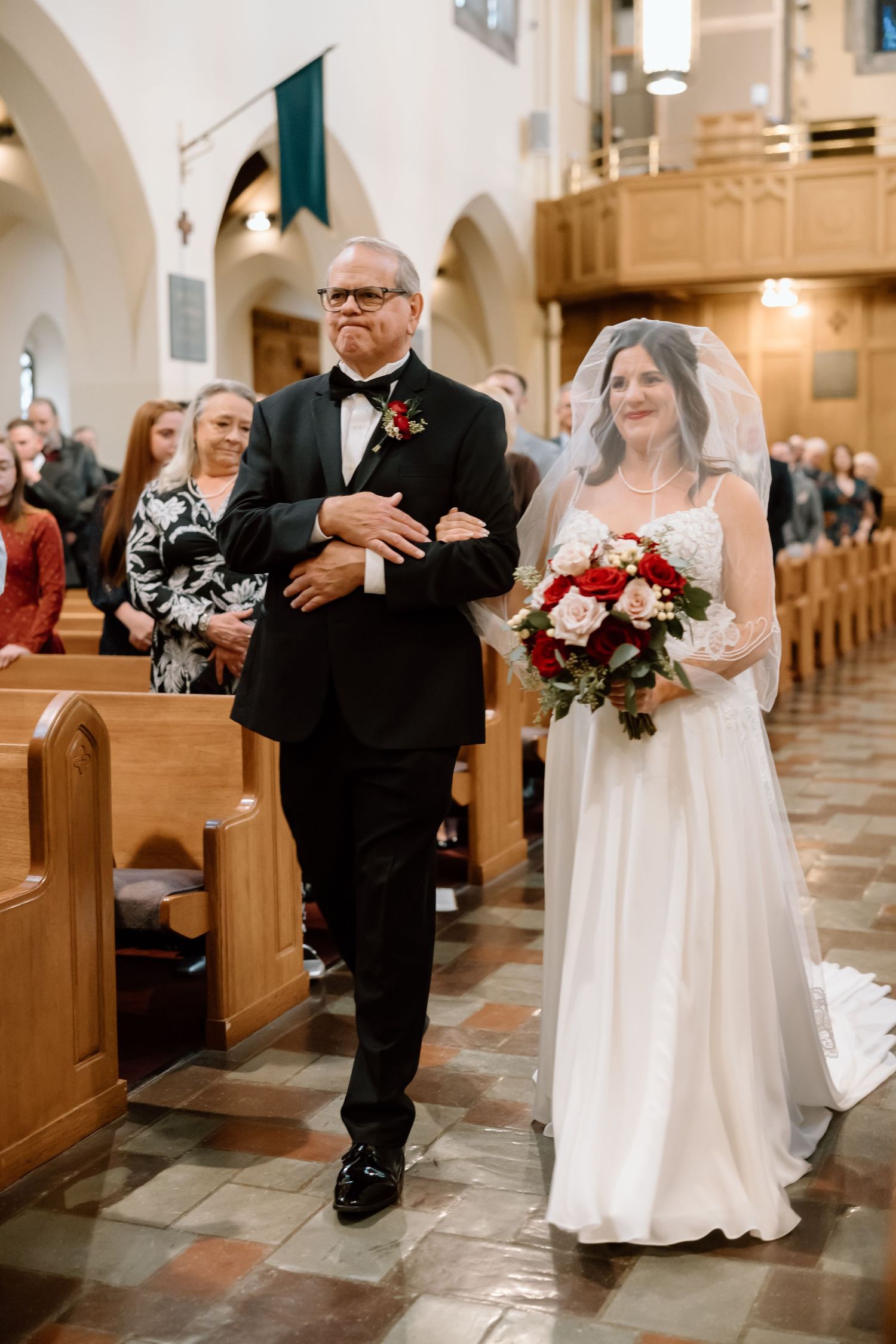 A bride walks down the church aisle with her escort during a traditional wedding ceremony.