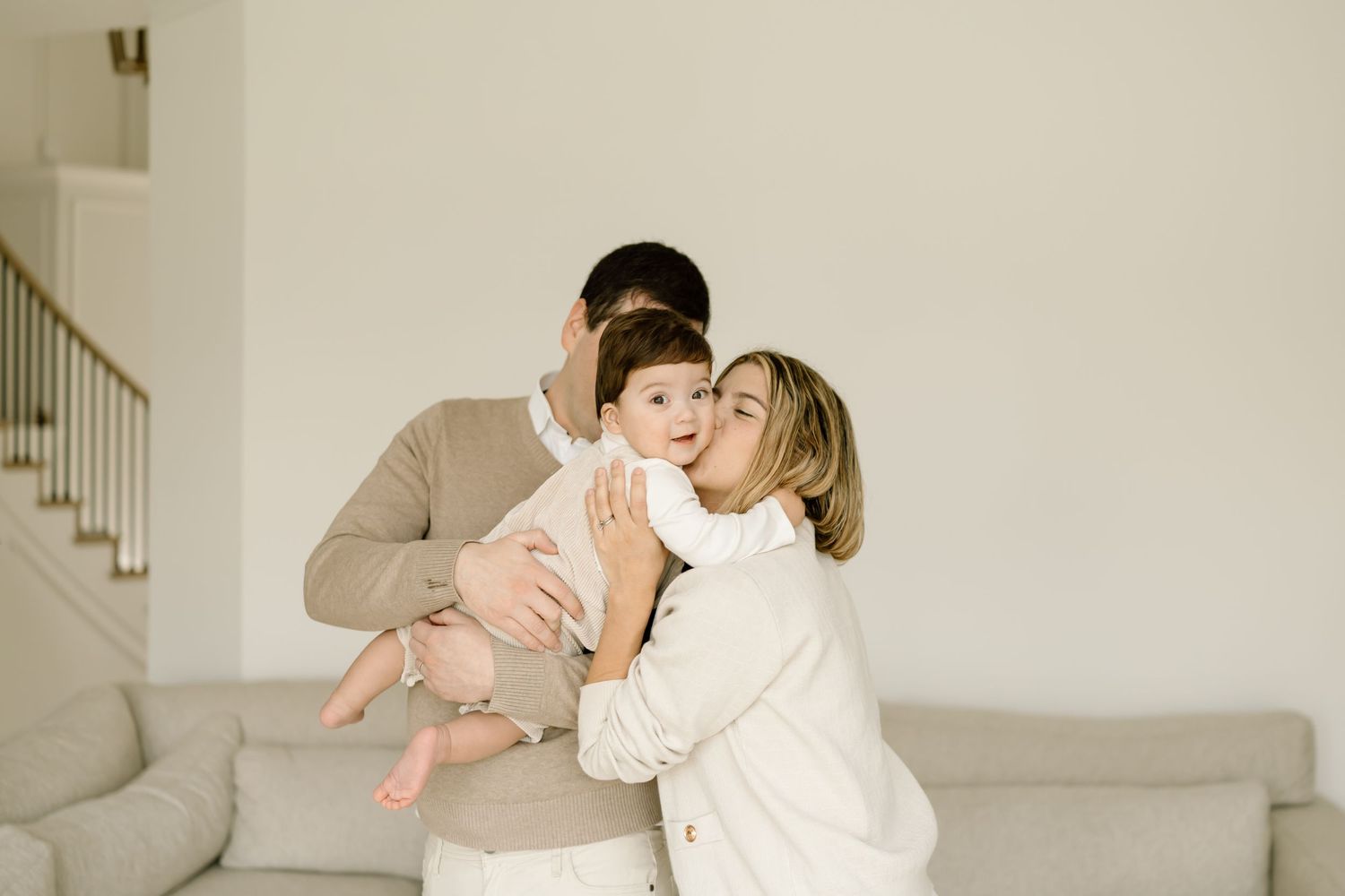 A family shares an intimate moment together while standing in their bright, minimalist living room.