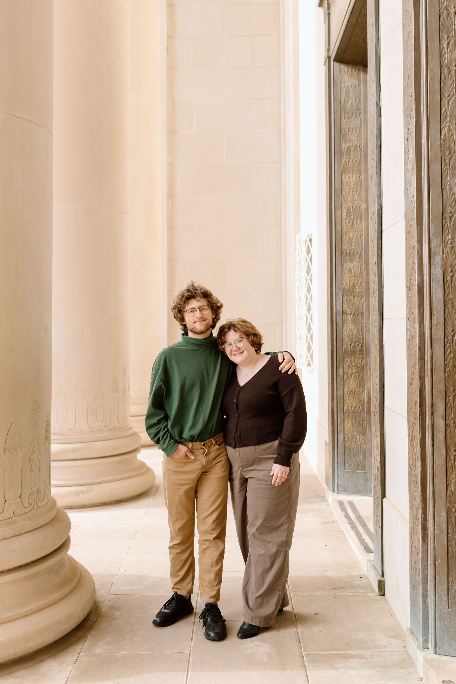 Three sequential photos show a couple posing playfully between classical white stone columns in an elegant setting.
