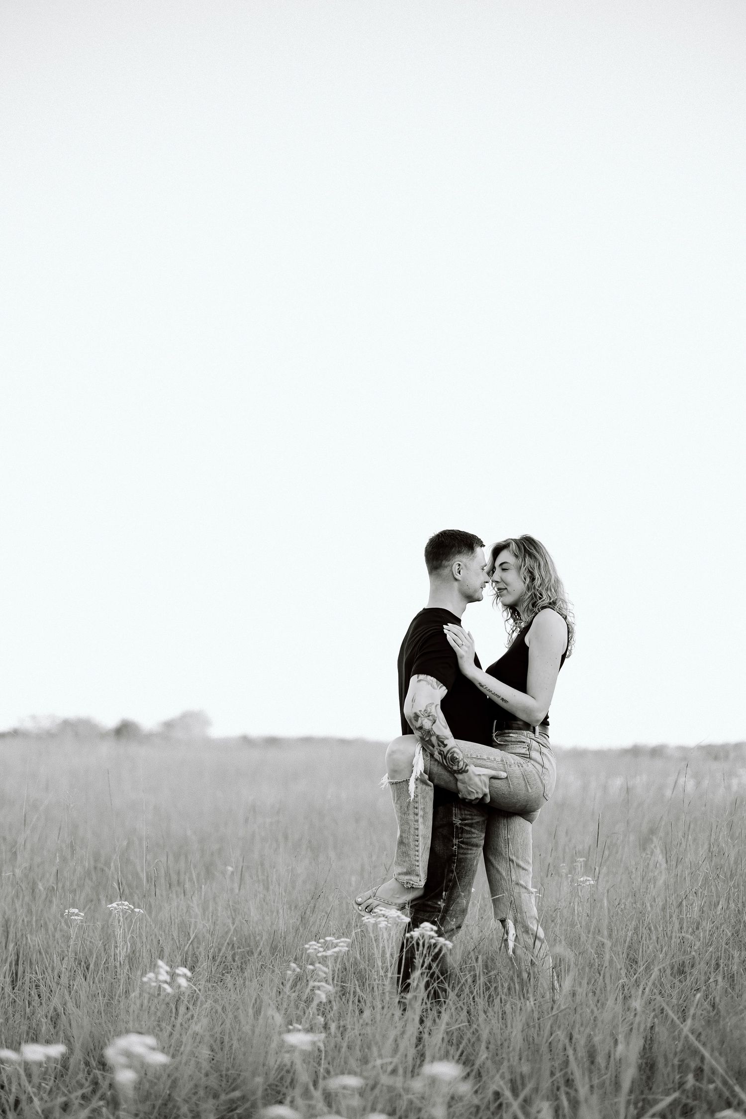A romantic black and white photo series showing a couple embracing in a serene meadow field.