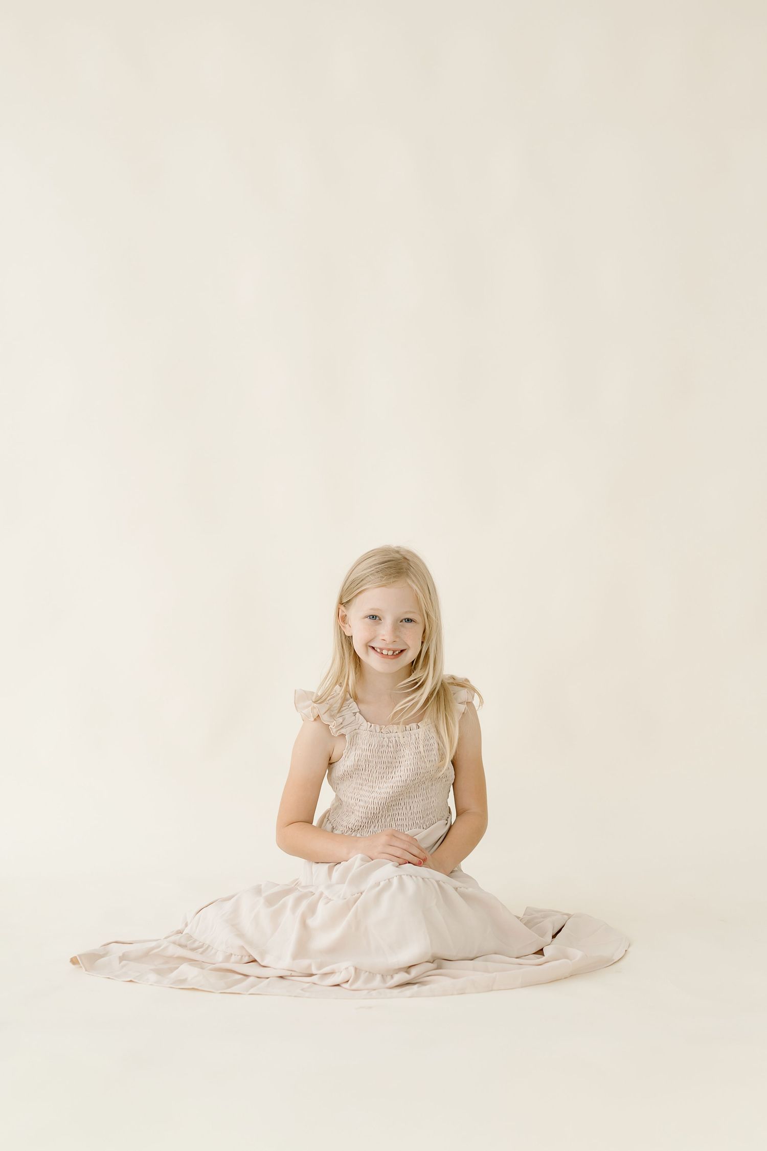 A sequence of three photos showing a child in a white dress sitting on a light-colored backdrop.
