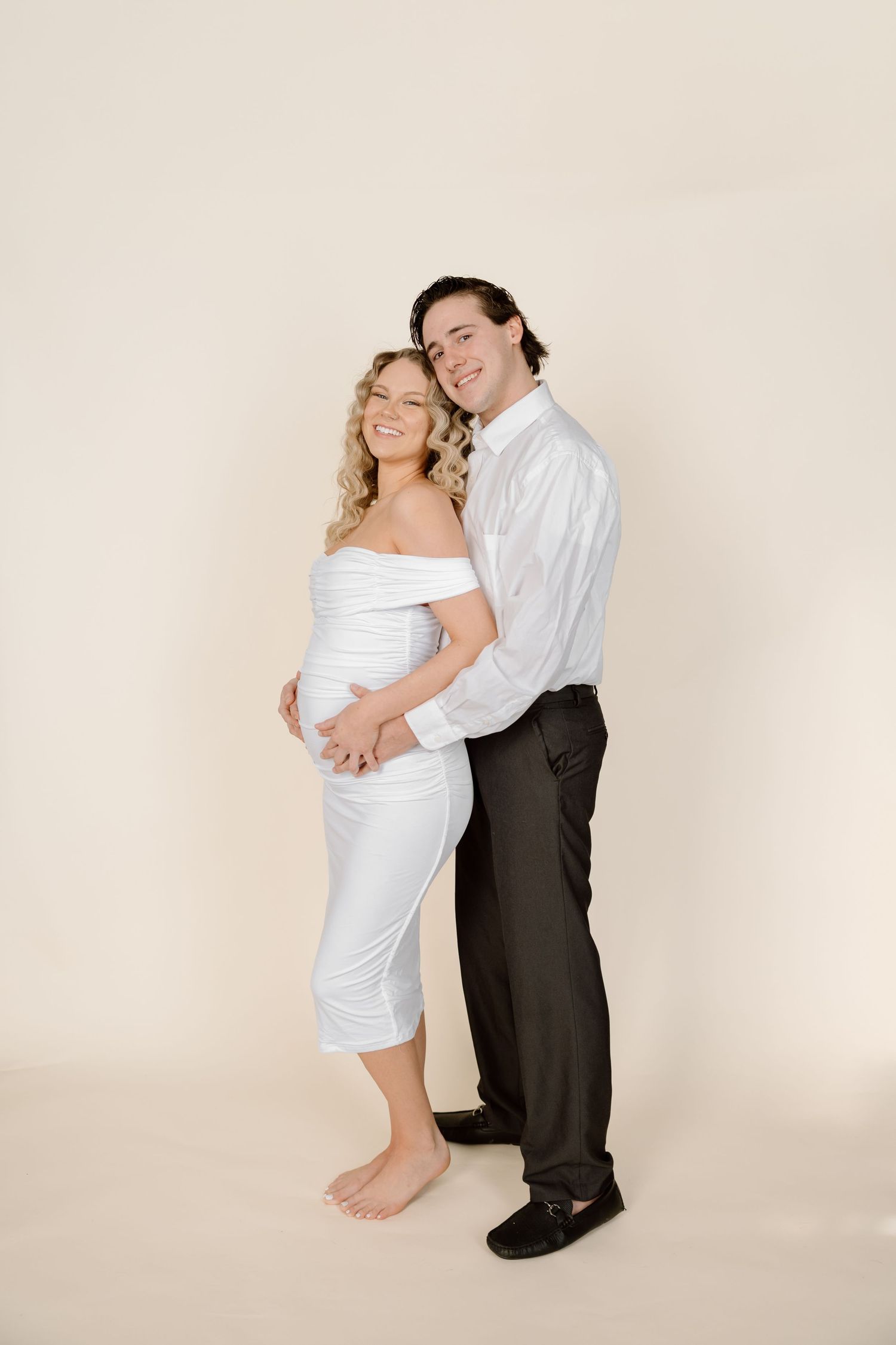 A romantic maternity photoshoot sequence showing a couple in white and black attire against a neutral background.
