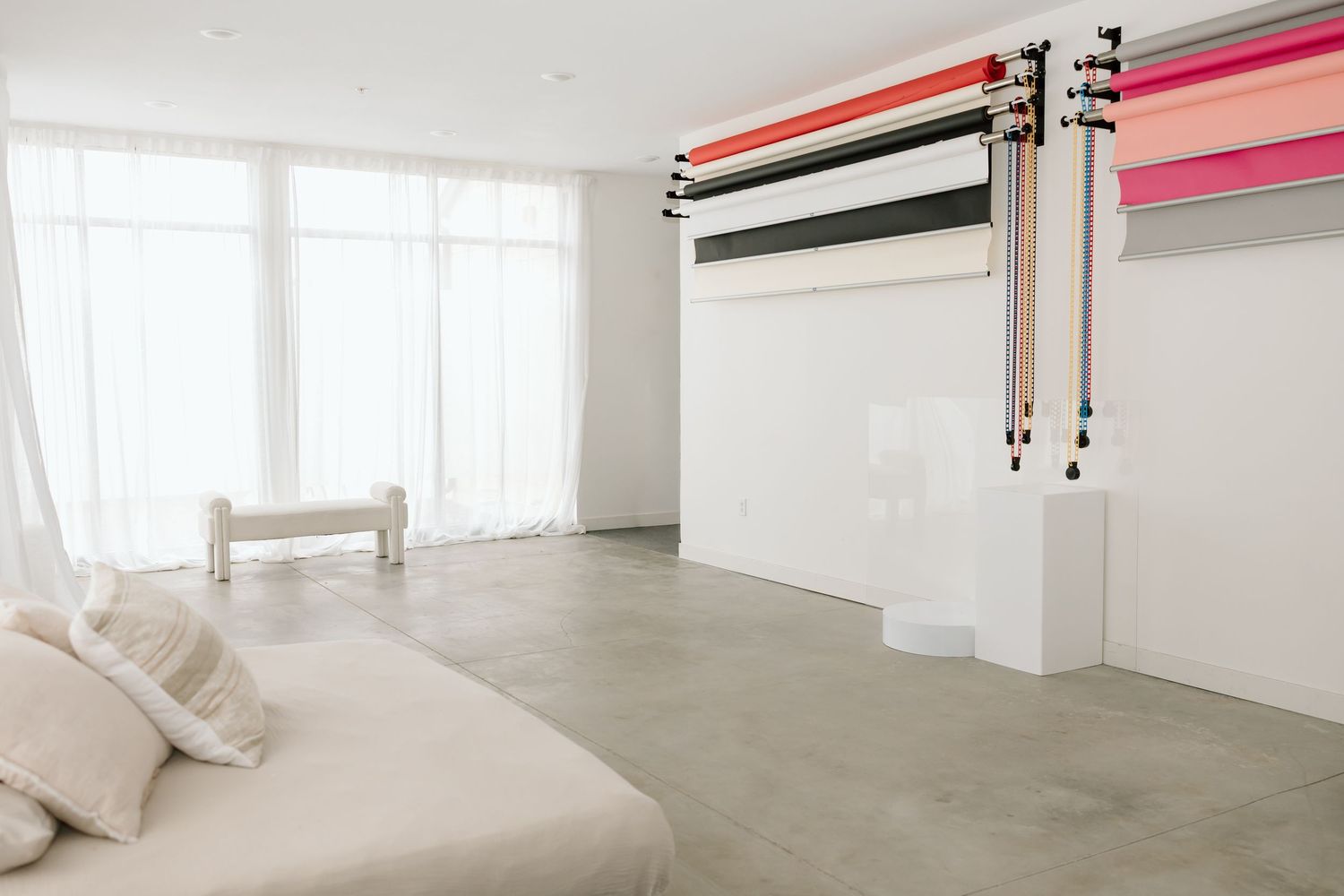 Bright and airy modern bedroom interior with white walls, pink accents, and natural light streaming through windows.