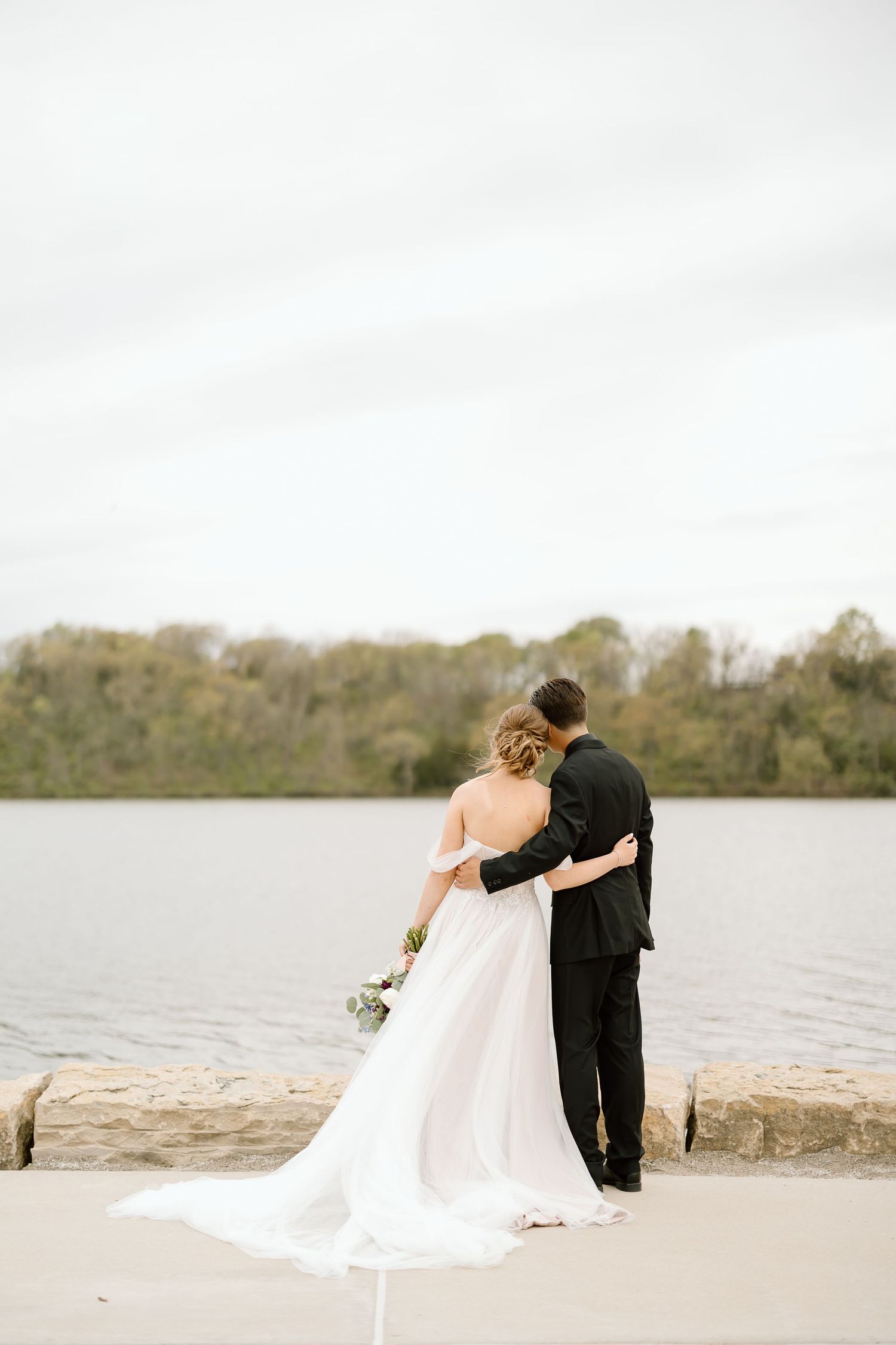 Newlyweds sharing an intimate moment while overlooking a serene lake.
