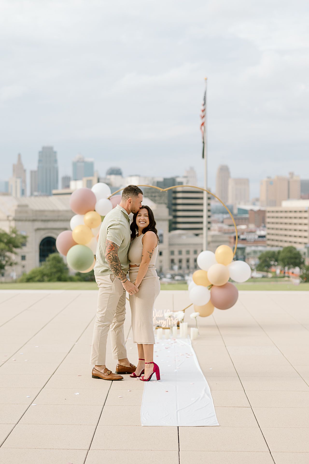 A tender moment captured on a city rooftop with decorative balloons and a white runner.