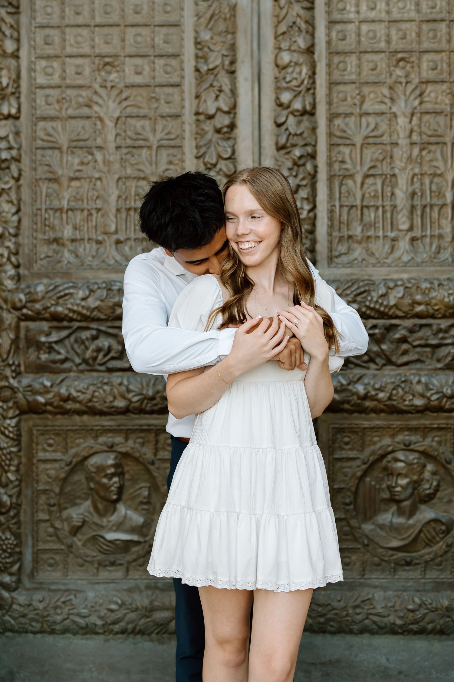 Romantic couple in white outfits embracing against a textured stone wall in a series of candid shots.