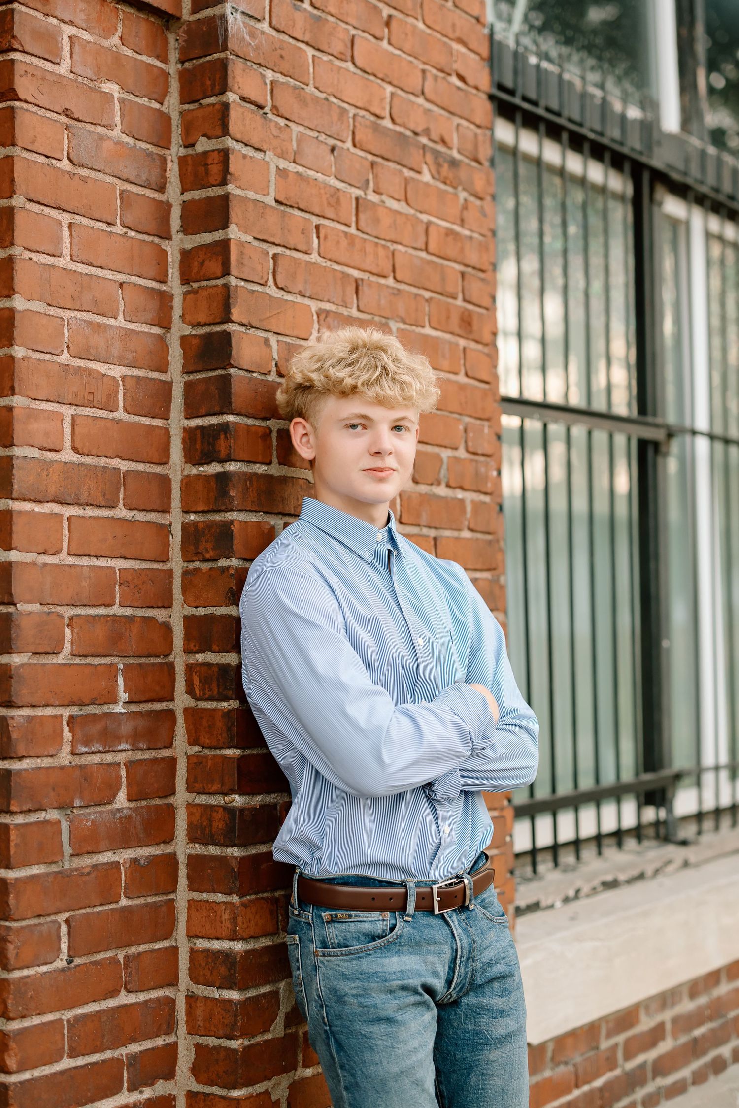 Three connected photos against a brick wall with windows showing someone in a light blue button-down shirt and jeans.