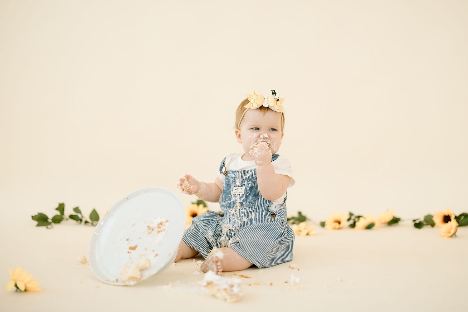 Baby in light blue romper lays on cream colored blanket during professional milestone photo session.