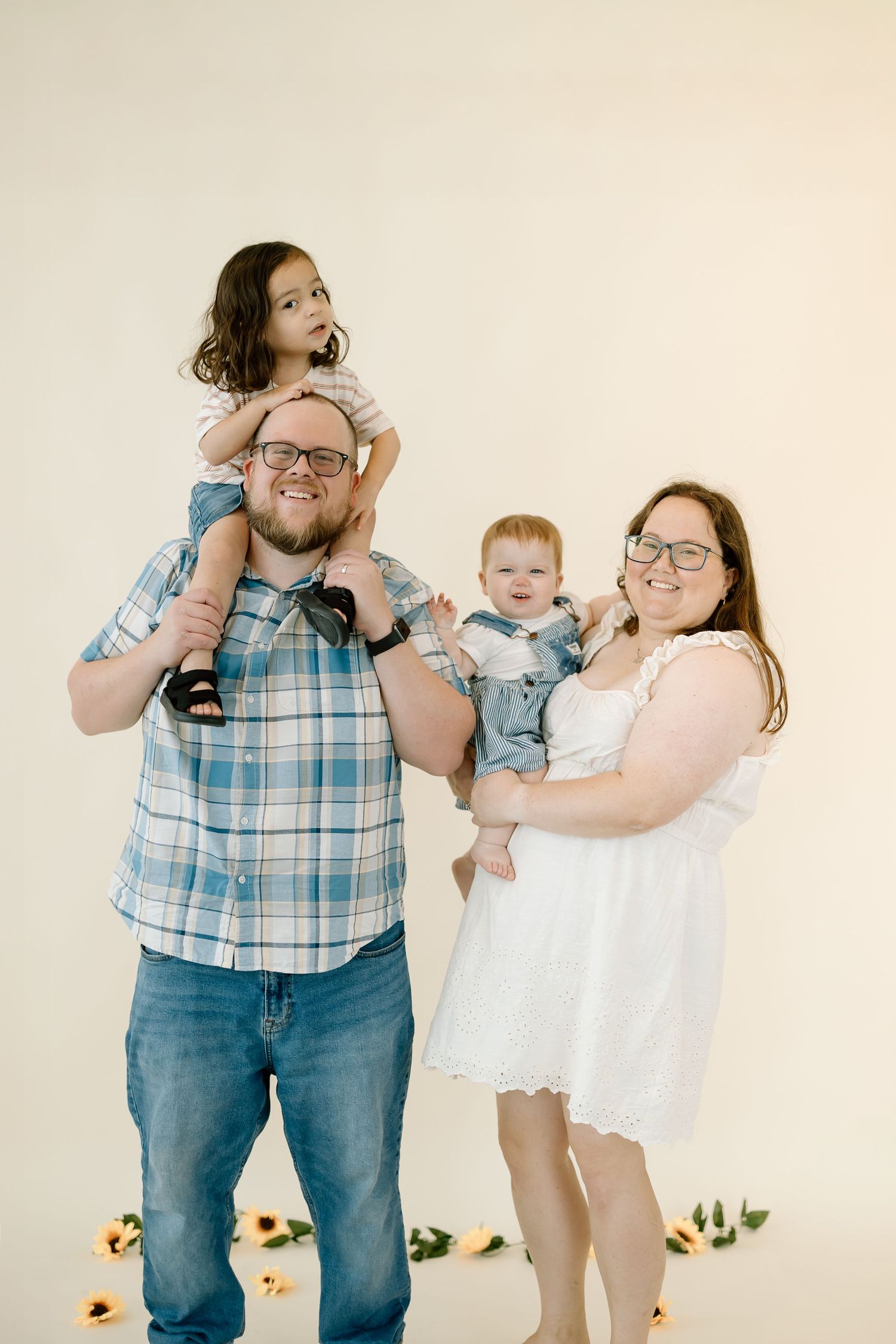 A family in coordinating blue and white outfits poses playfully together in a studio setting against a light backdrop.