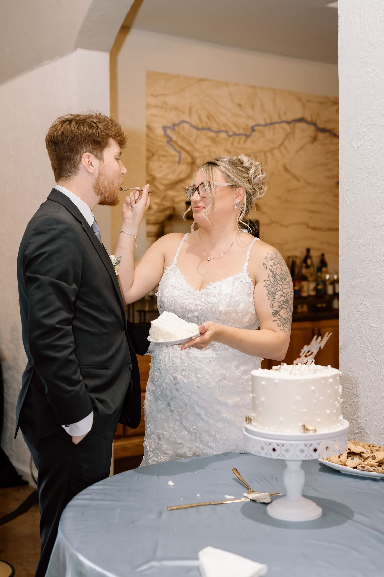 A couple shares a playful moment while cutting their wedding cake at their reception.
