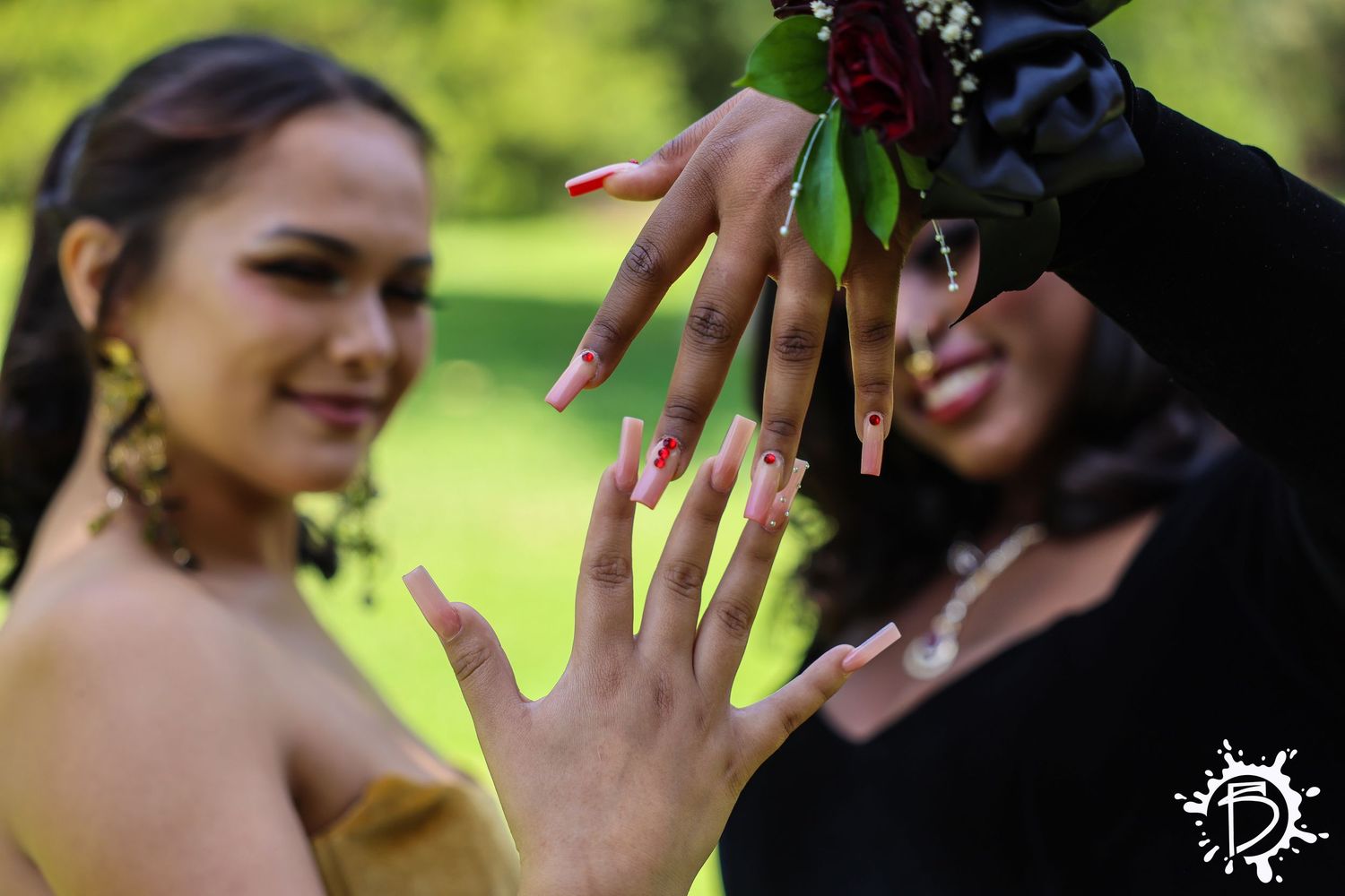 Two elegant hands showcasing engagement rings against a blurred green outdoor background with leaves.