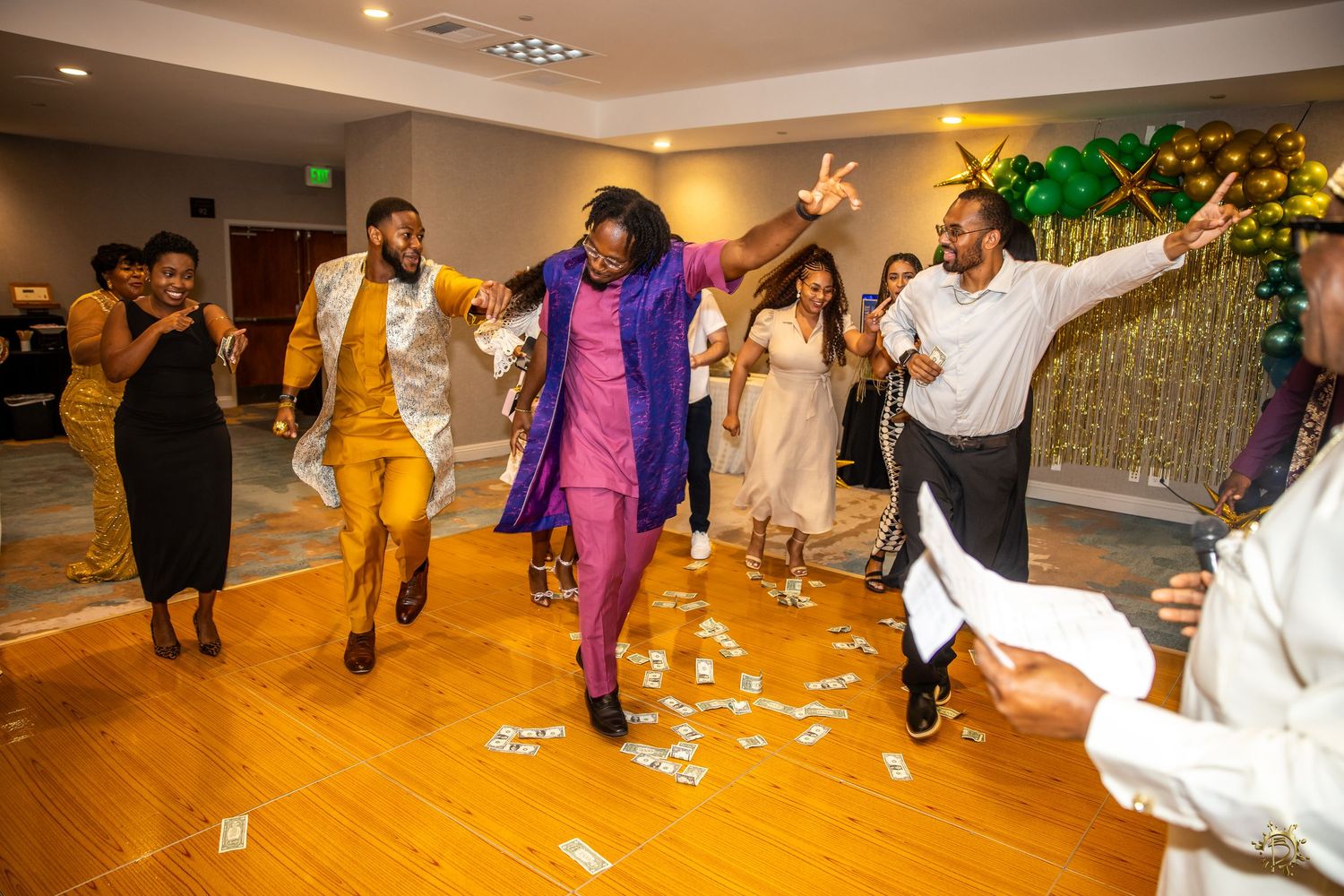 Graduation party as son and friends dance/celebrate together on a wooden dance floor at an indoor reception venue.