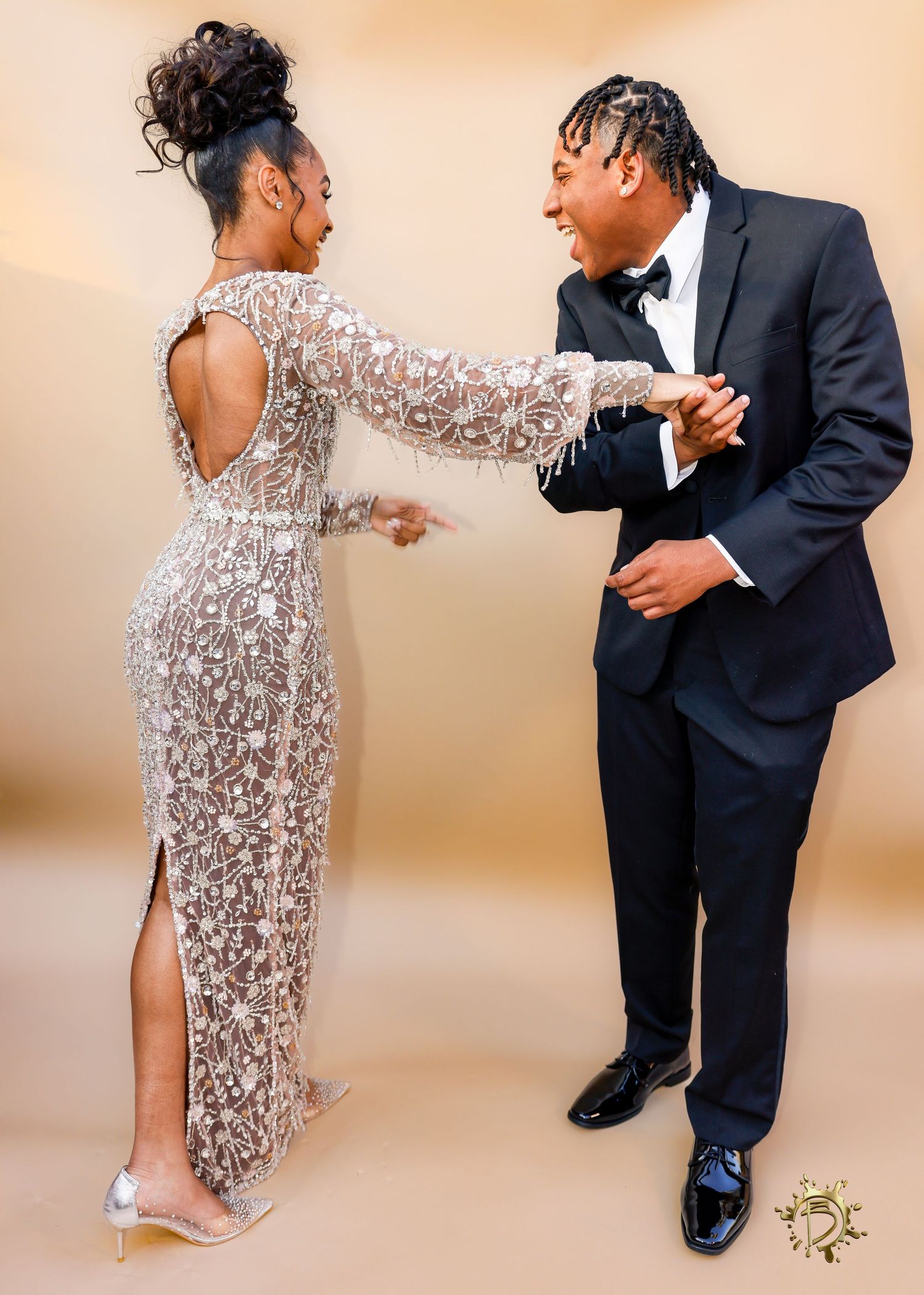 Couple in formal attire share a playful moment, with woman wearing sequined gown and man in dark suit.