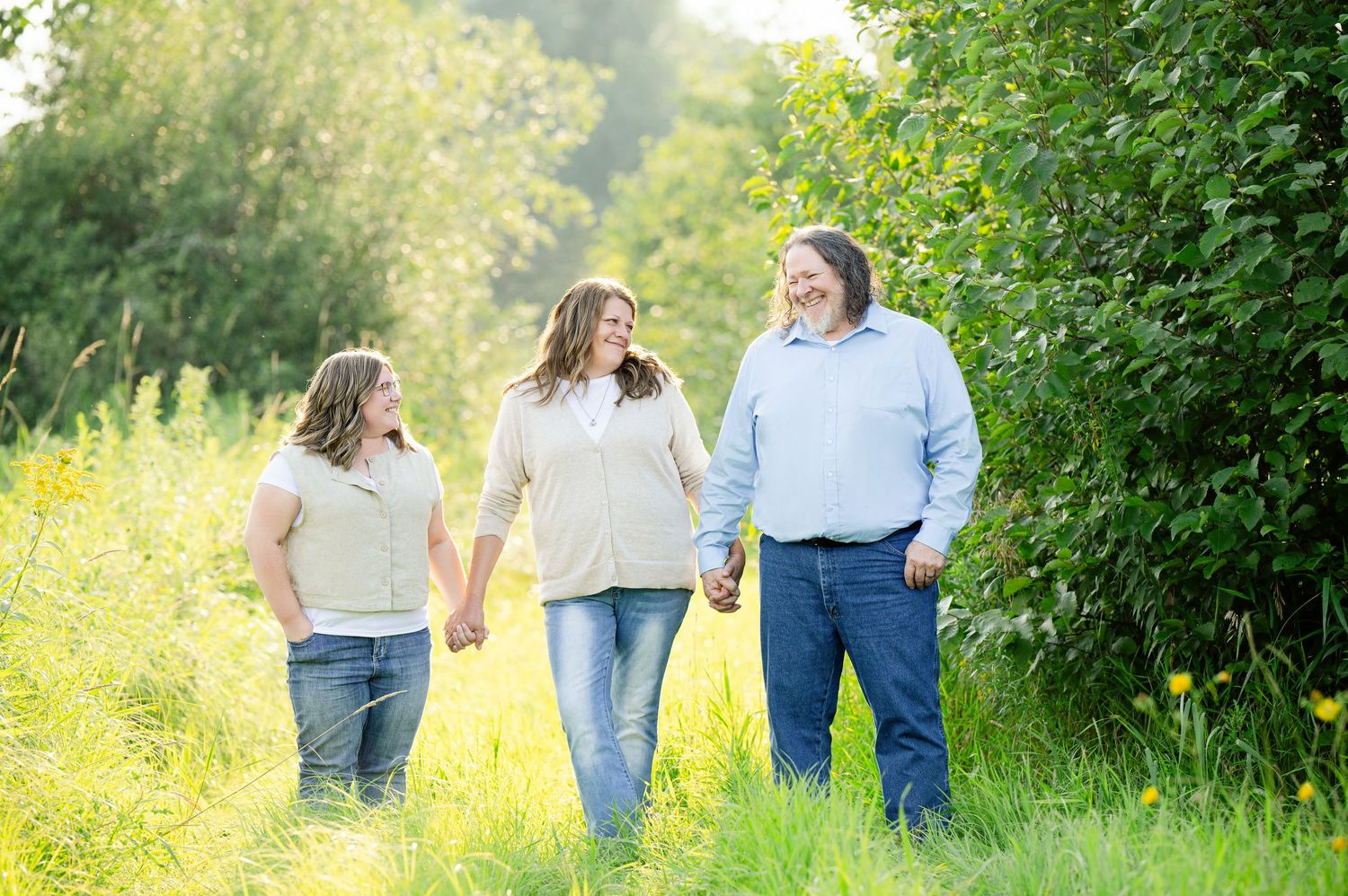 Family walking together on a sunny grass path surrounded by lush greenery during a summer outdoor session.