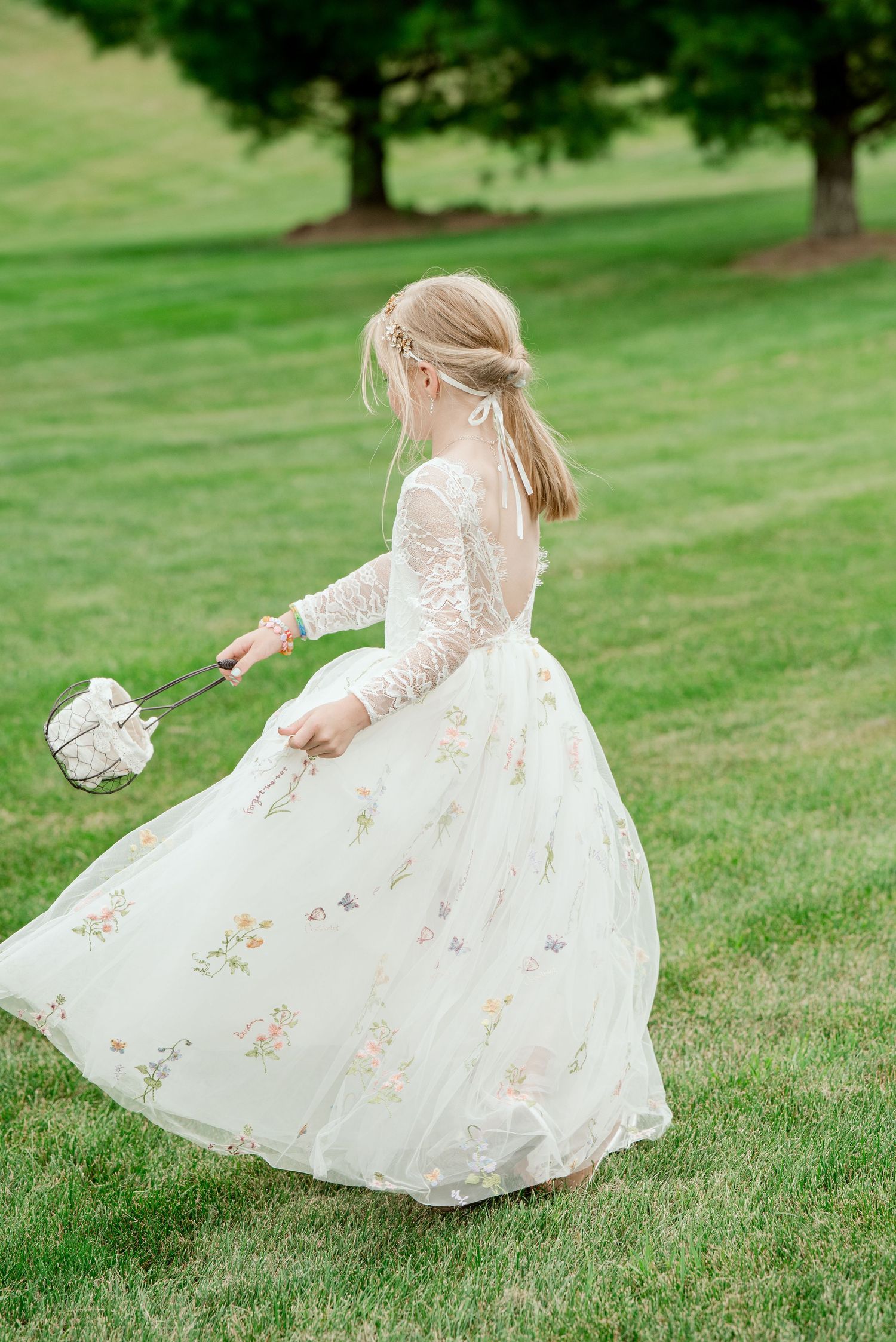 A white lace flower girl dress twirls gracefully on a green lawn in a series of connected action shots.