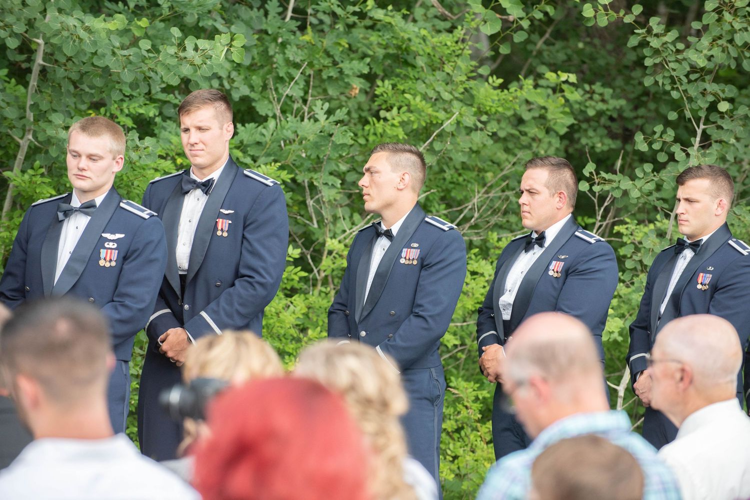 Wedding ceremony guests gathered outdoors in formal attire with suits and dresses standing in a row during summer. Zimmerman MN Weddings