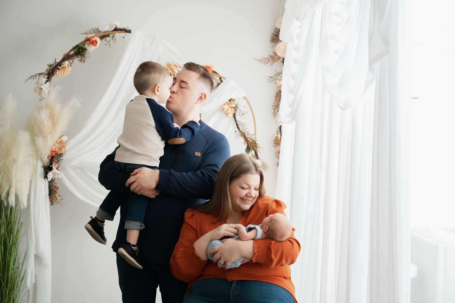 In central Minnesota a series of candid newborn + family moments captured in white curtained room showing playful interactions and embraces.