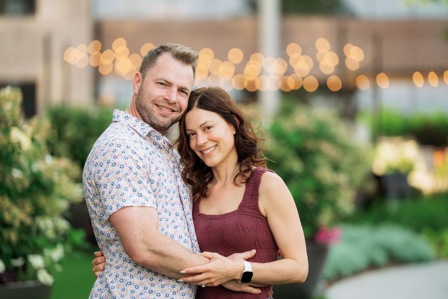 A couple shares a romantic moment while dancing together in an outdoor garden setting at sunset.