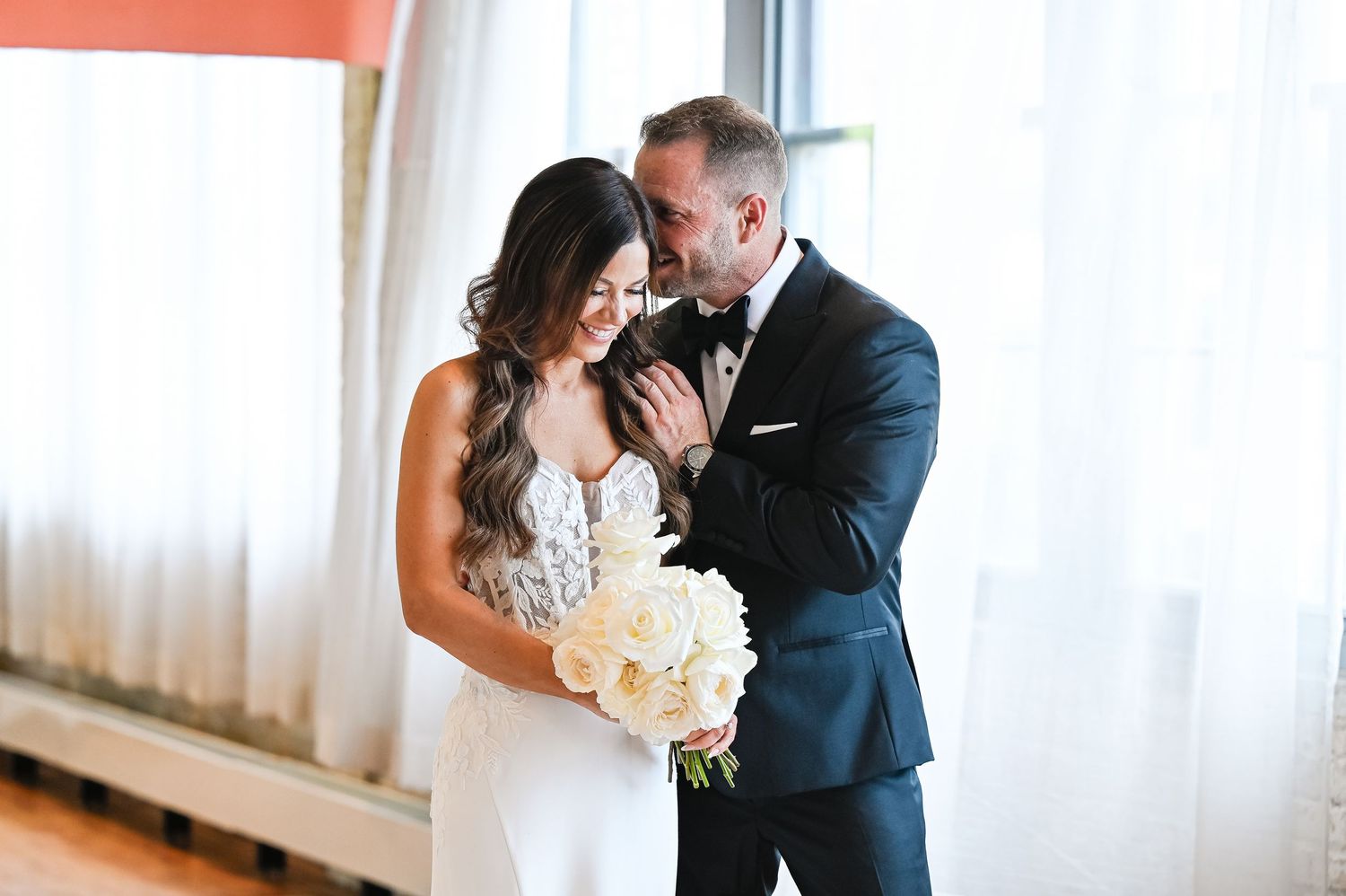 Intimate wedding moment captured in a bright sunlit corridor.