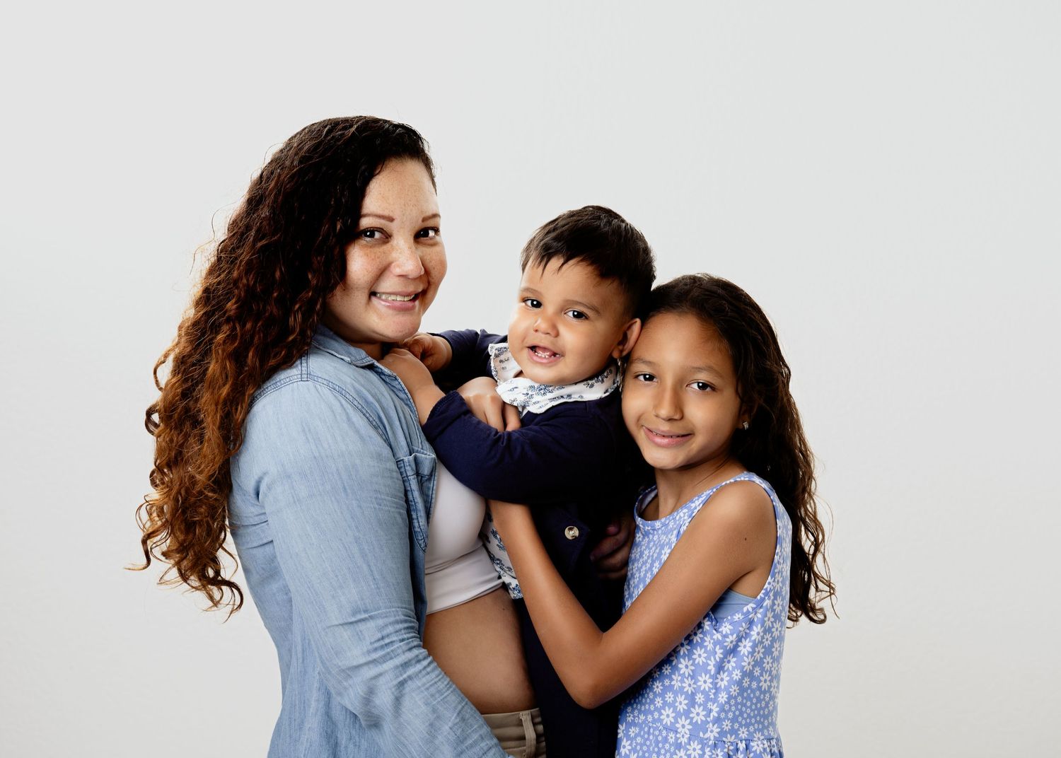A family of three wearing coordinated blue outfits poses together against a white background.