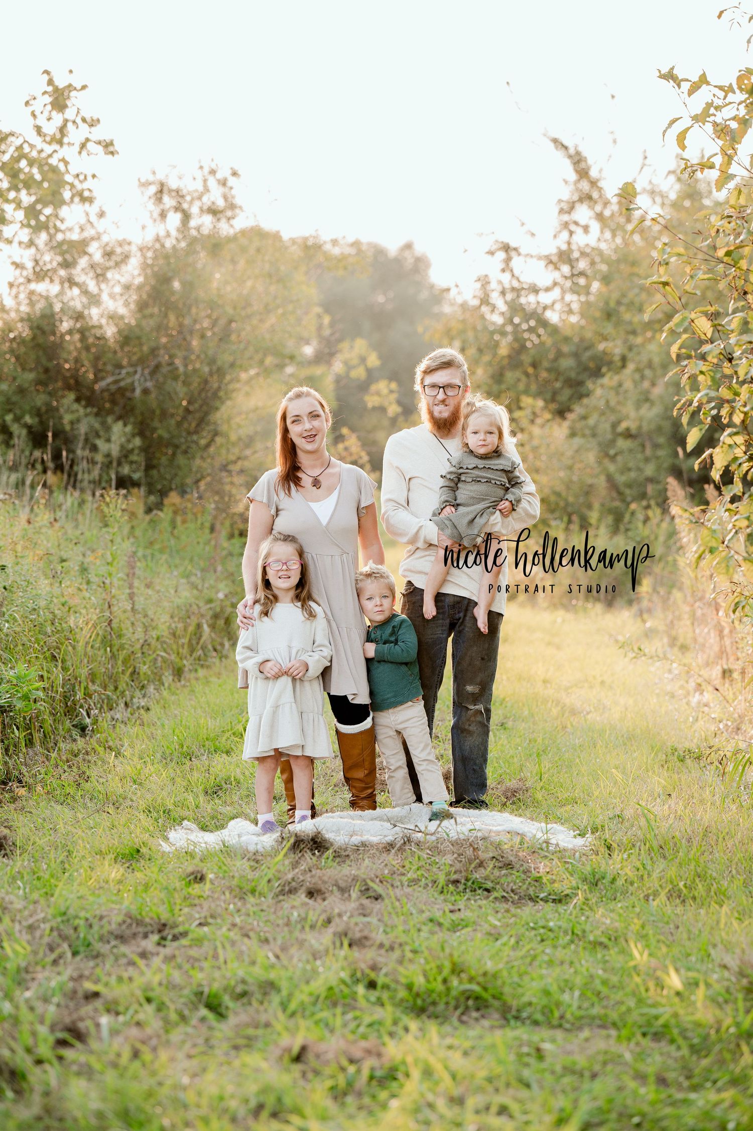A family stands together on a blanket in a sun-dappled nature path.
