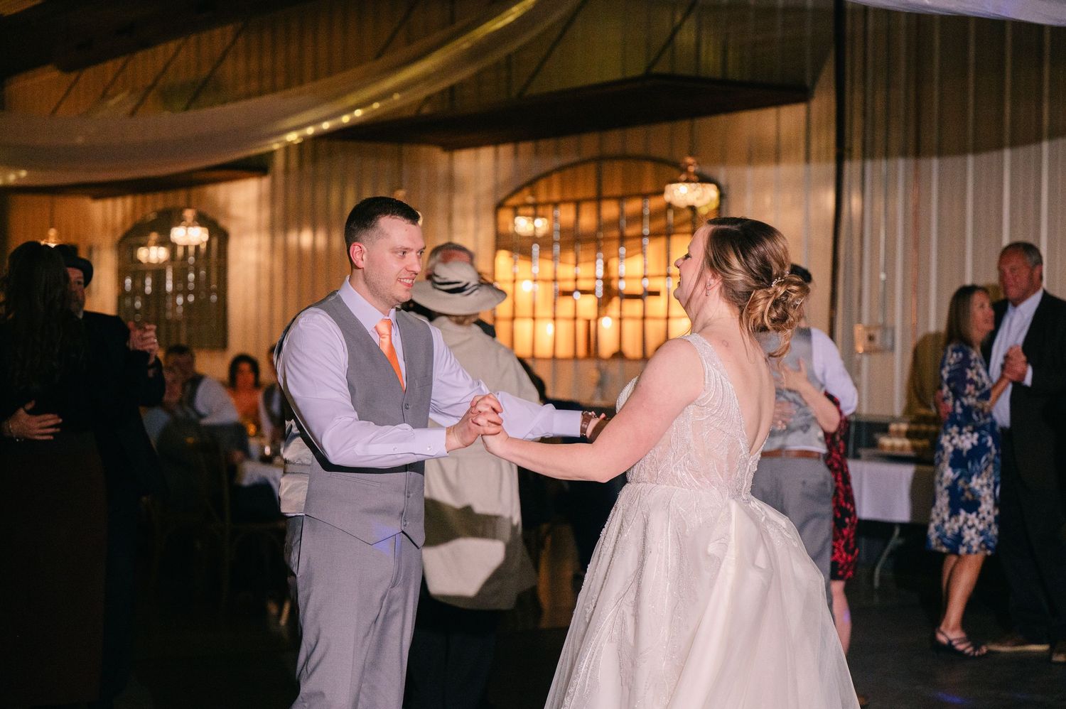 Bride and groom share their first dance at elegant wedding reception with warm ambient lighting.