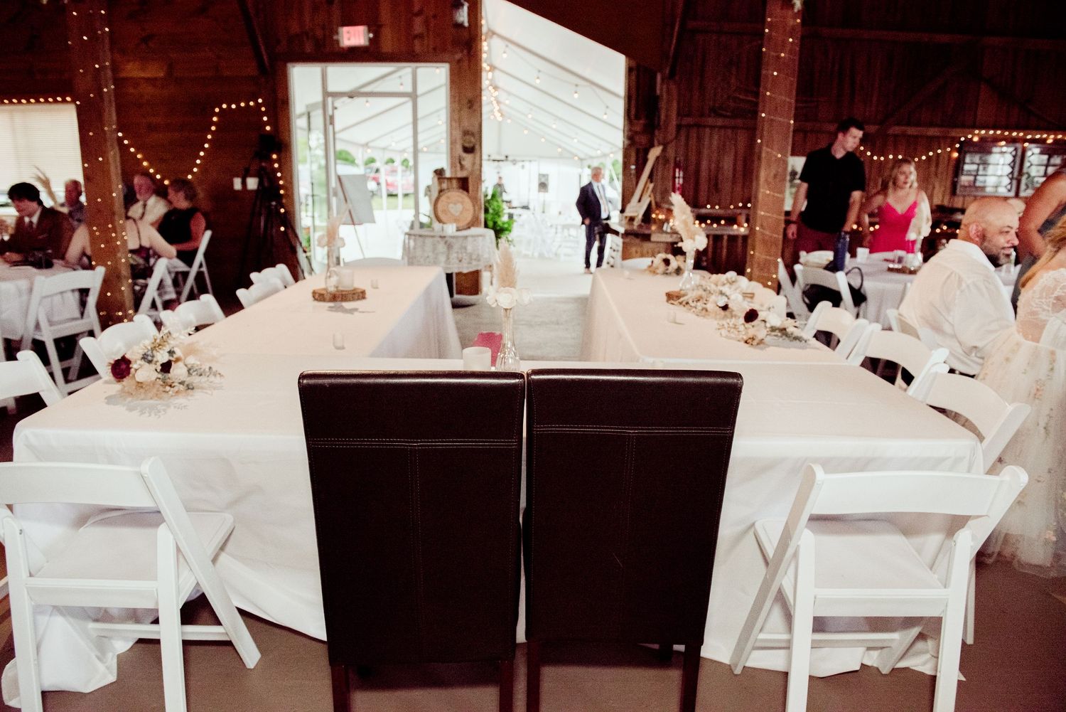 Reception venue decorated with elegant white chairs and tables for a formal wedding celebration.