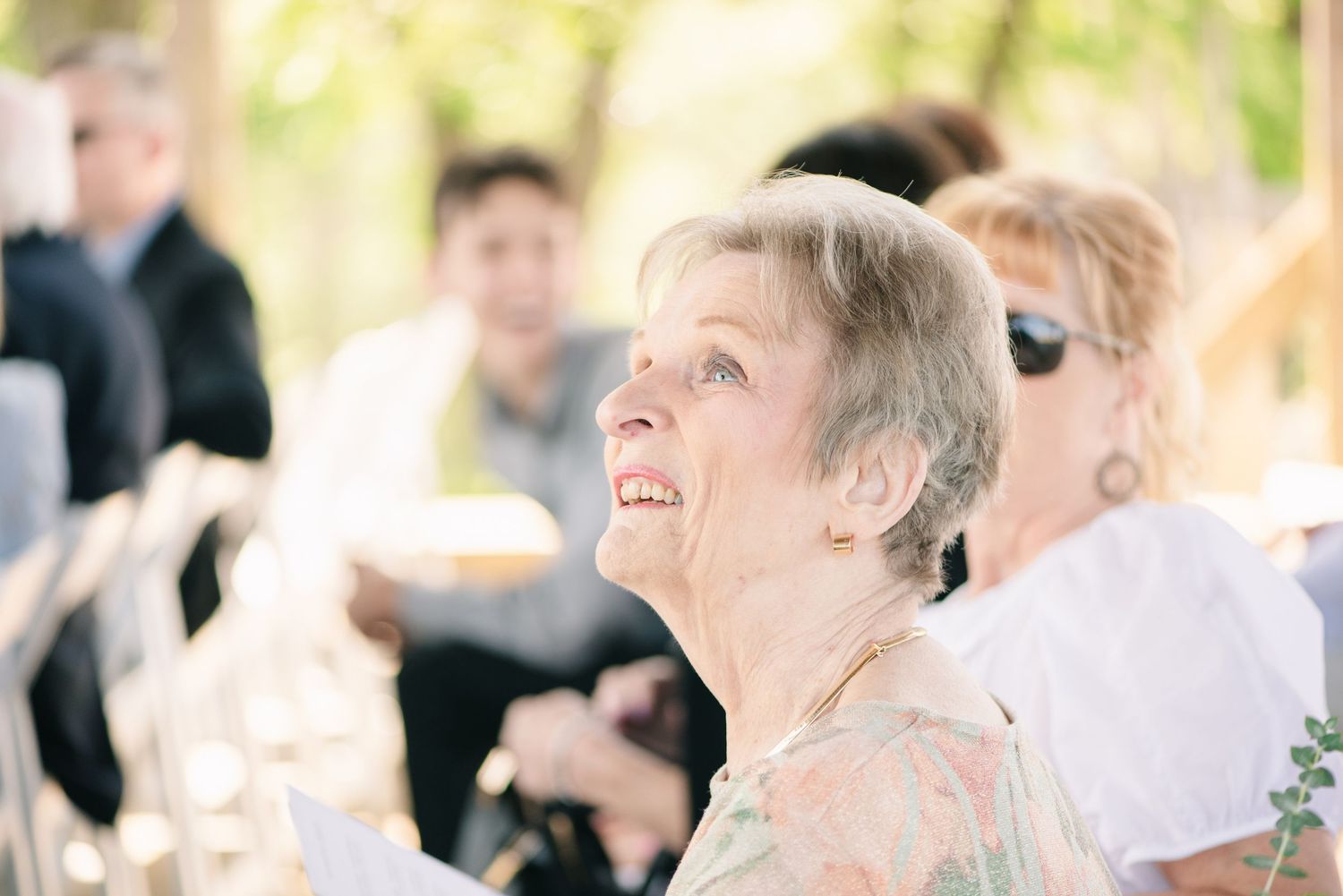 Central MN Wedding Photos - Elderly woman smiling and looking up joyfully at an outdoor wedding reception event.