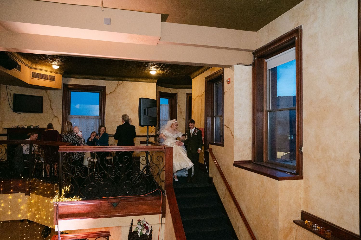 Central MN Wedding Photos | Bride and groom descending ornate staircase at elegant wedding venue with warm lighting.