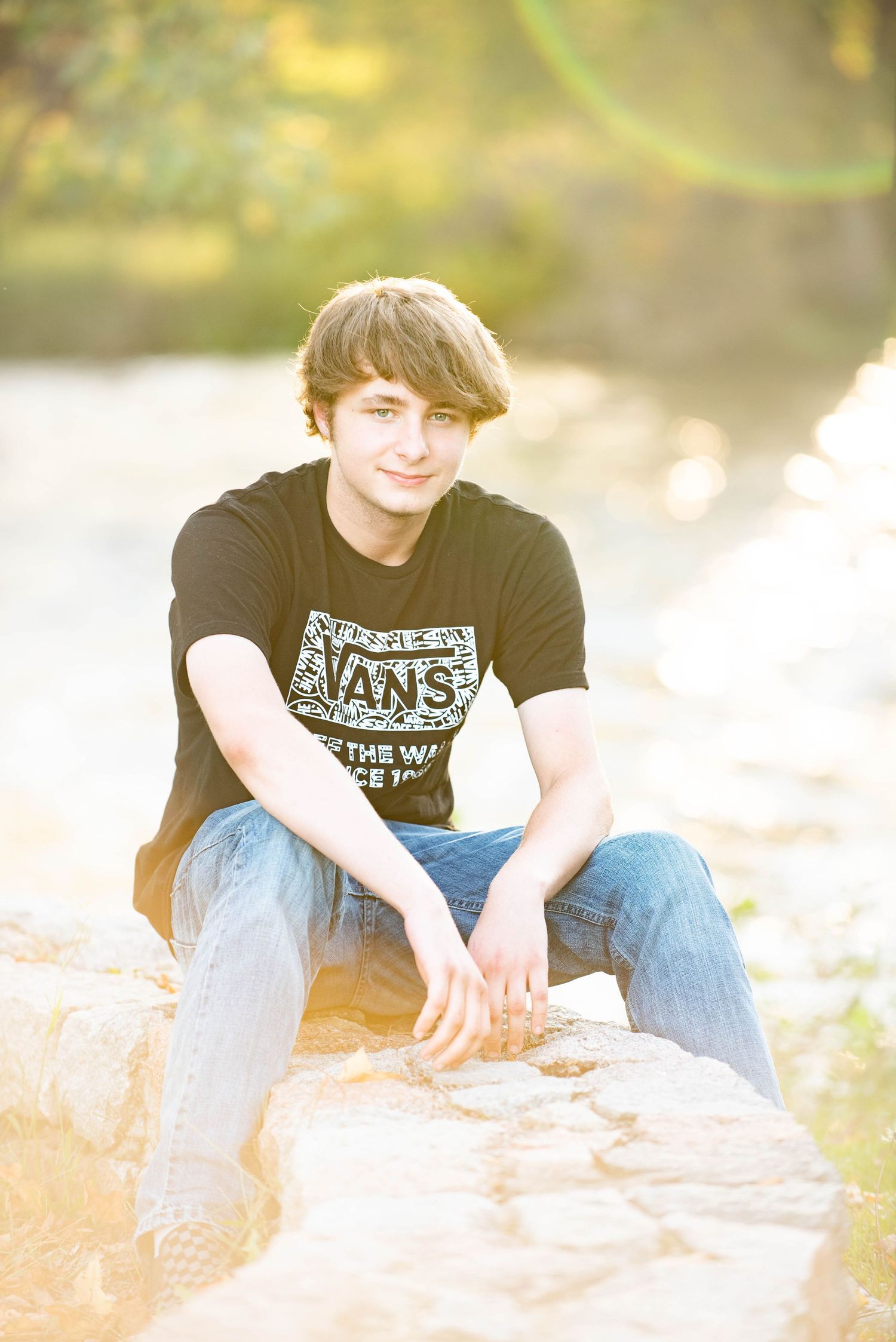 Person in casual wear relaxes on rocky surface with sunlit natural backdrop.